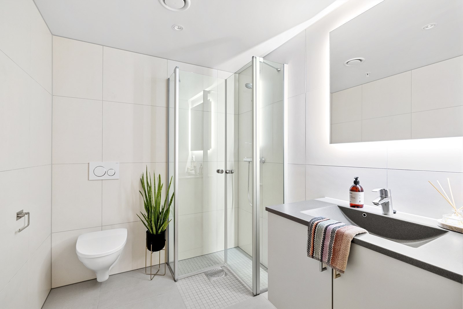 Badet med inngang fra gangen er helfliset med 60x60 fliser i nøytrale fargetoner, noe som gir et tidløst uttrykk. Galleribilde