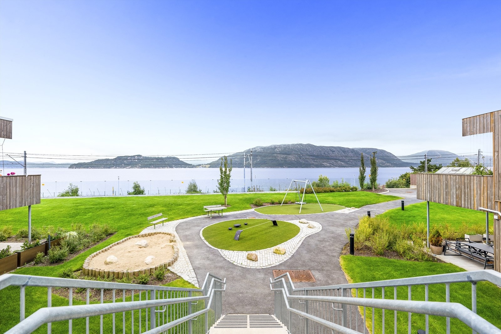 Upåklagelig utsikt mot Gandsfjorden og fjellene bak. Her fra fellesareal. Det er montert glassrekkverk som demper lyd fra togskinnene. Galleribilde