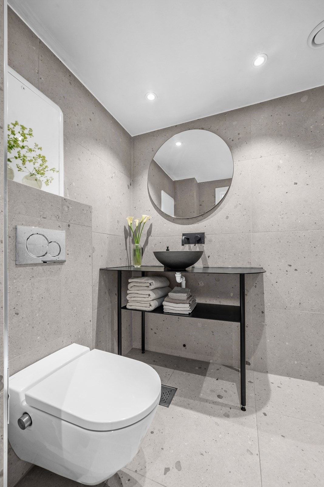 Badet har veggfestet klosett fra Laufen (type spyletoalett) , spesiallaget baderomsmøbel fra Kampen Mekaniske med åpent benkeskap og speil over servant Galleribilde