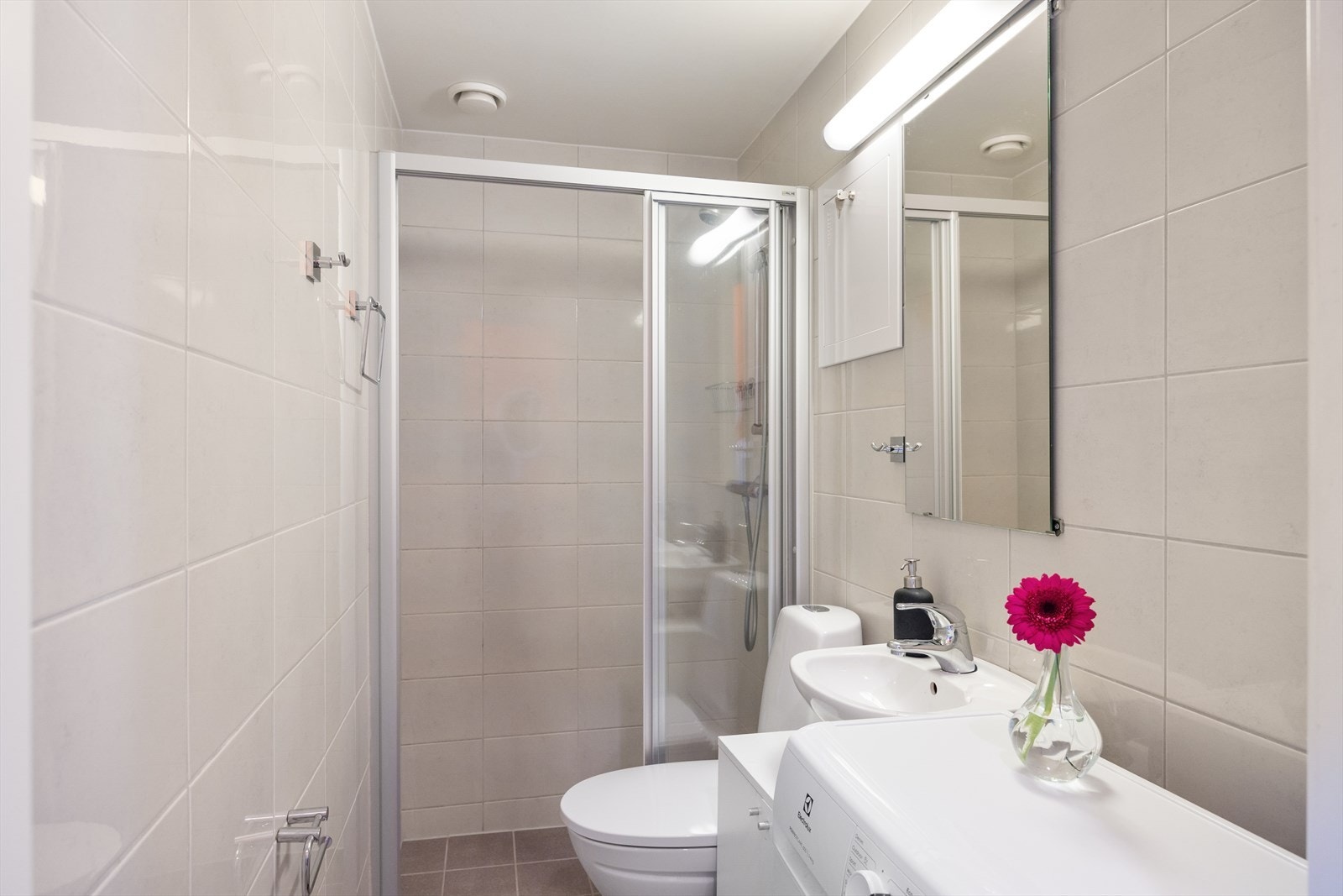Badet inneholder WC, dusjplass, servant med ettgreps blandebatteri og innredning, samt opplegg for vaskemaskin. Galleribilde