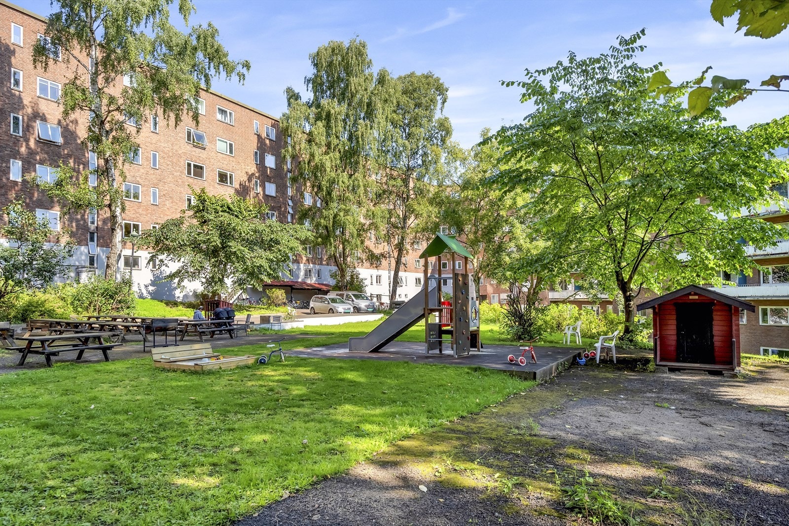 Tomten er opparbeidet med plen, beplantning, sittegrupper og lekeområde Galleribilde