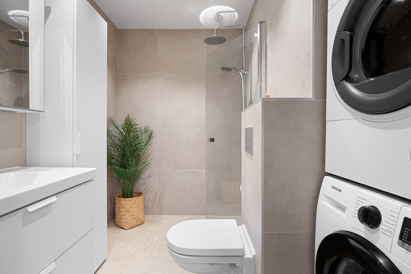 Flislagt gulv med gulvvarme. Flislagte vegger.
Nedsenket himling med downlights. Vegghengt servantinnredning med skuffer. Ovenpåliggende servant med ett-greps armatur. Speilskap med overlys og stikkontakt over servant. Galleribilde