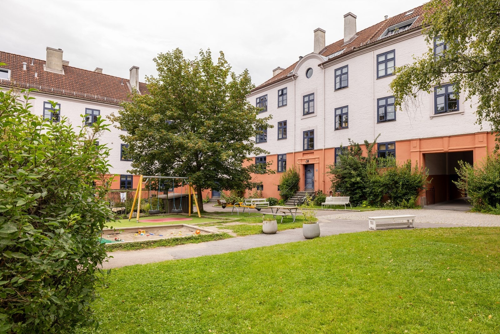 Den skjermede bakgården har en fin lekeplass for de små, og er rikt beplantet med trær, busker og blomster - oppleves som en oase Galleribilde