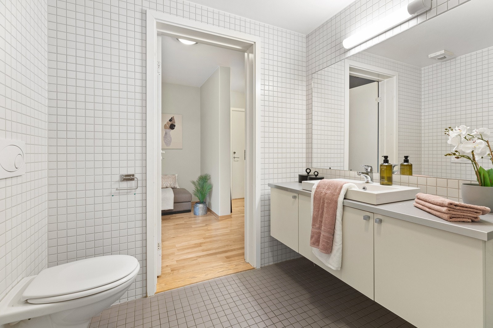 Badet er innredet med servantskap, innfelt speil, veggmontert klosett, opplegg for vaskemaskin, samt nedsenket dusjsone med glassvegg. Galleribilde