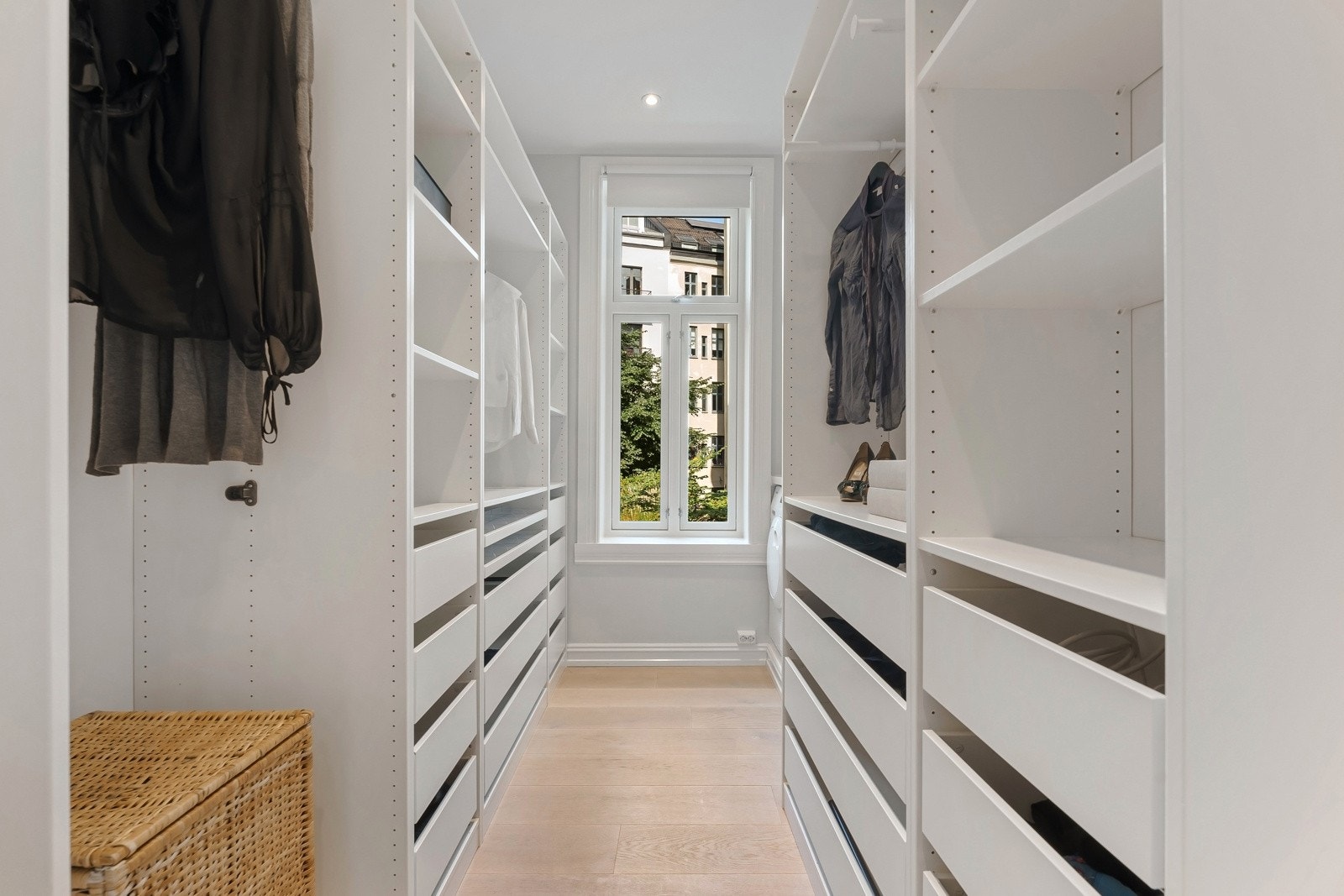 Store garderobeskap på hver sin side med garderobestammer med hyller, skuffer og oppheng. Galleribilde