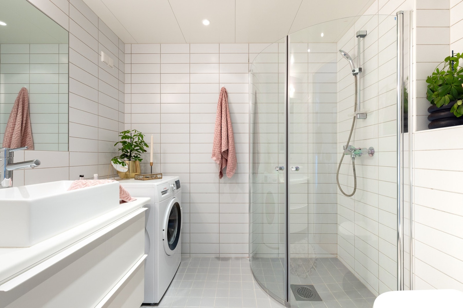 Badet inneholder innredning med glatte fronter og benkeplate av laminat og ovenpåliggende servant med ett-greps armatur. Speil over servant med overlys og stikkontakter ved vask. Videre har badet dusjhjørne med innfellbare glassdører. og vegghengt toalett Galleribilde