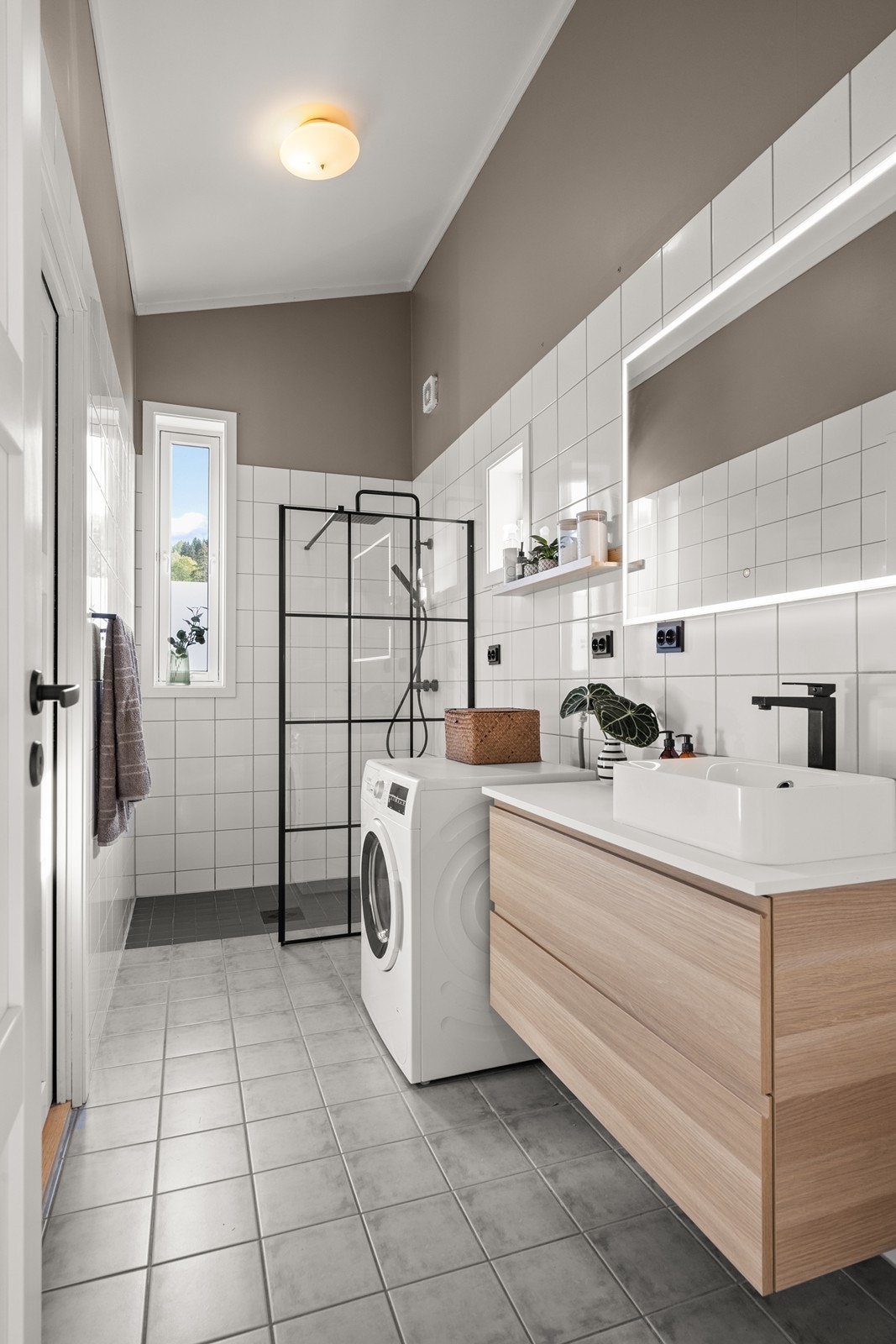 Badet er utstyrt med servant med underskap, speil med lys, dusjnisje m/regndusj og glassvegg, toalett samt opplegg for vaskemaskin Galleribilde