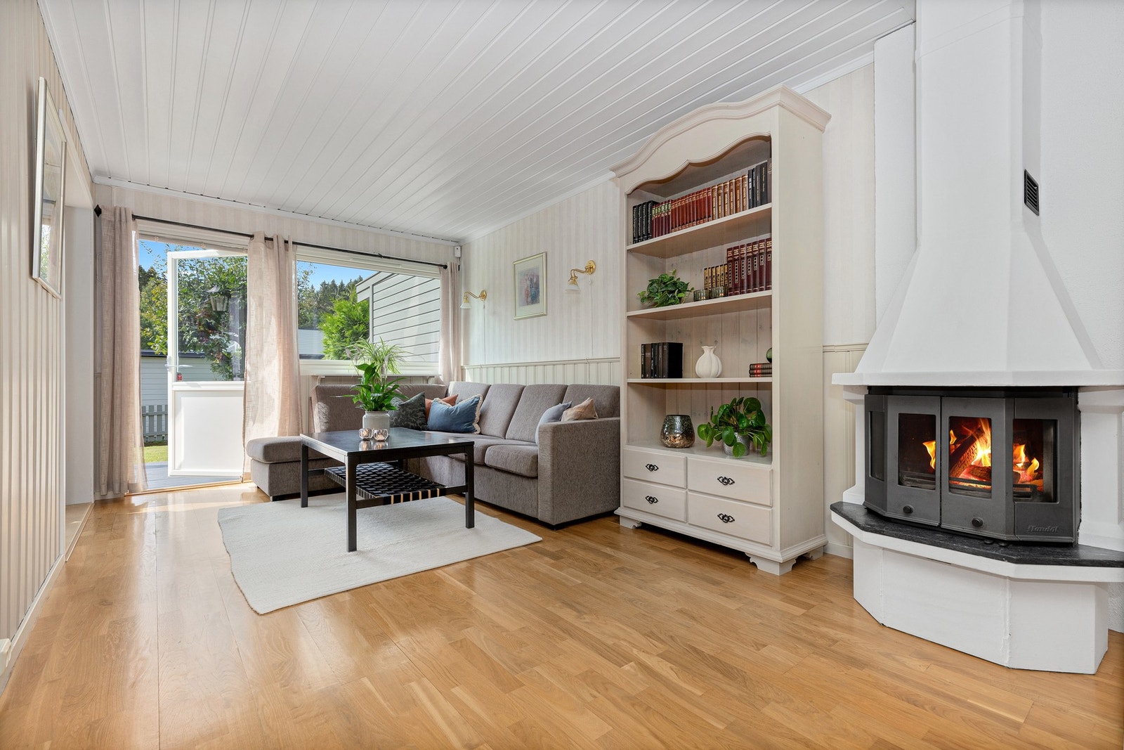 Det er en flott peis i stuen og det er utgang til en stor og vestvendt terrasse og hage. Galleribilde