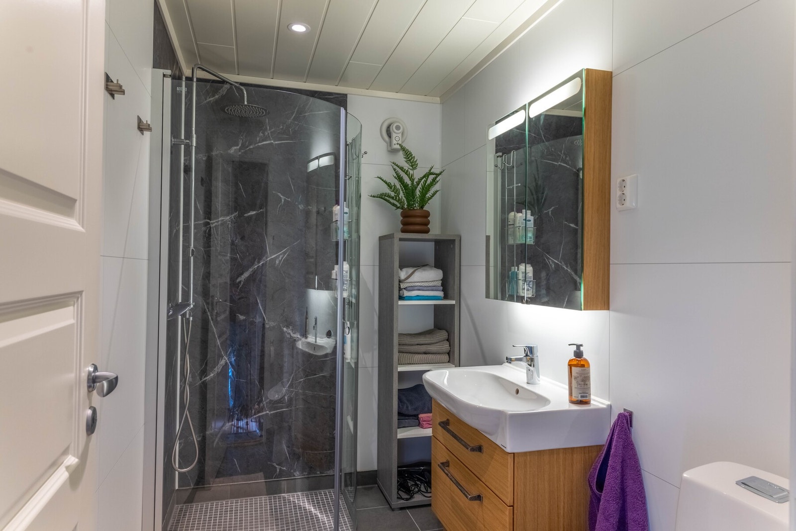 Fint bad med dusjhjørne med innfeldbare vegger, baderomsinnredning og toalett Galleribilde