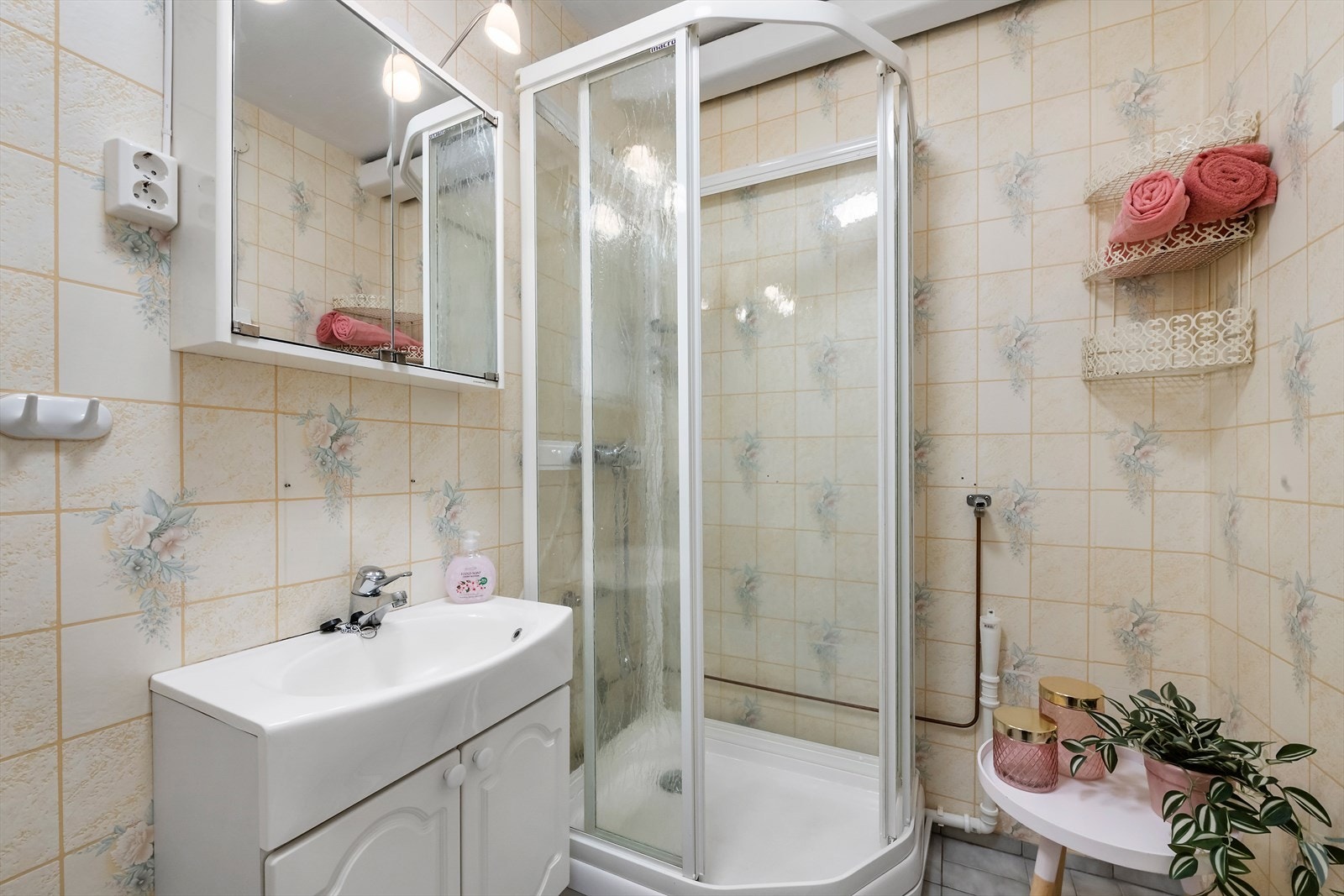 Badet har fliselagt gulv, våtroms-tapet på veggene og dusjkabinett, høyskap og baderomsinnredning med nedfelt vask. Galleribilde