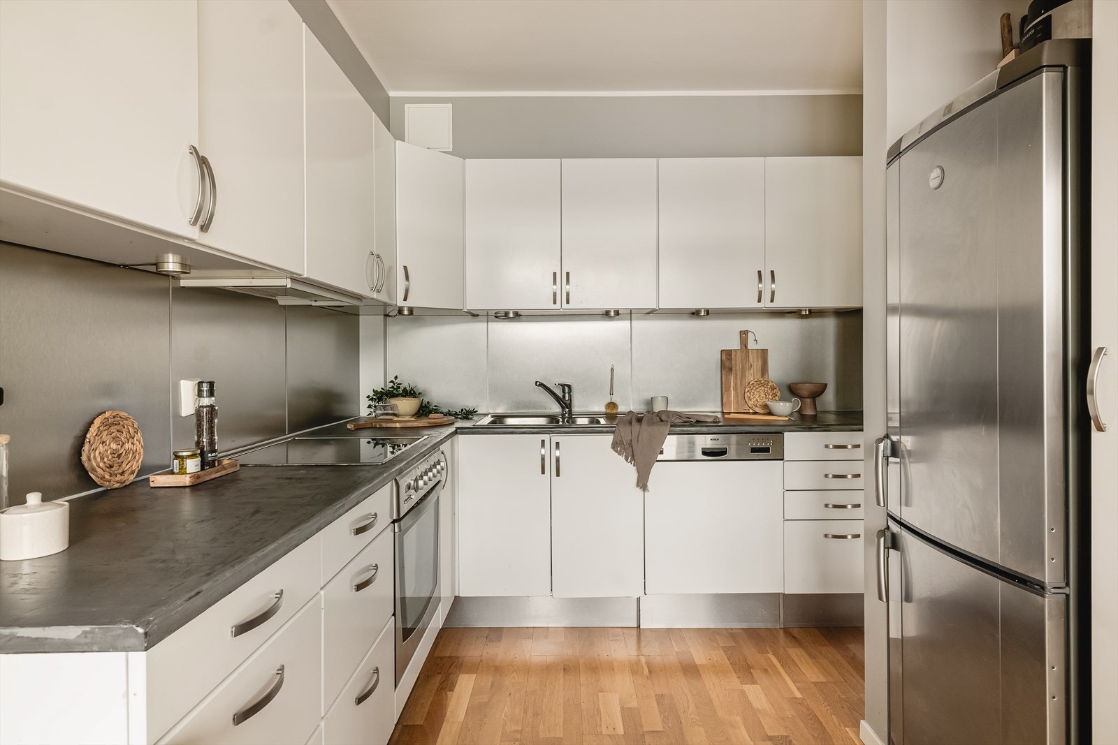 Stilren innredning i slette hvite fronter og splash boards over grå laminert benkeplate. Galleribilde