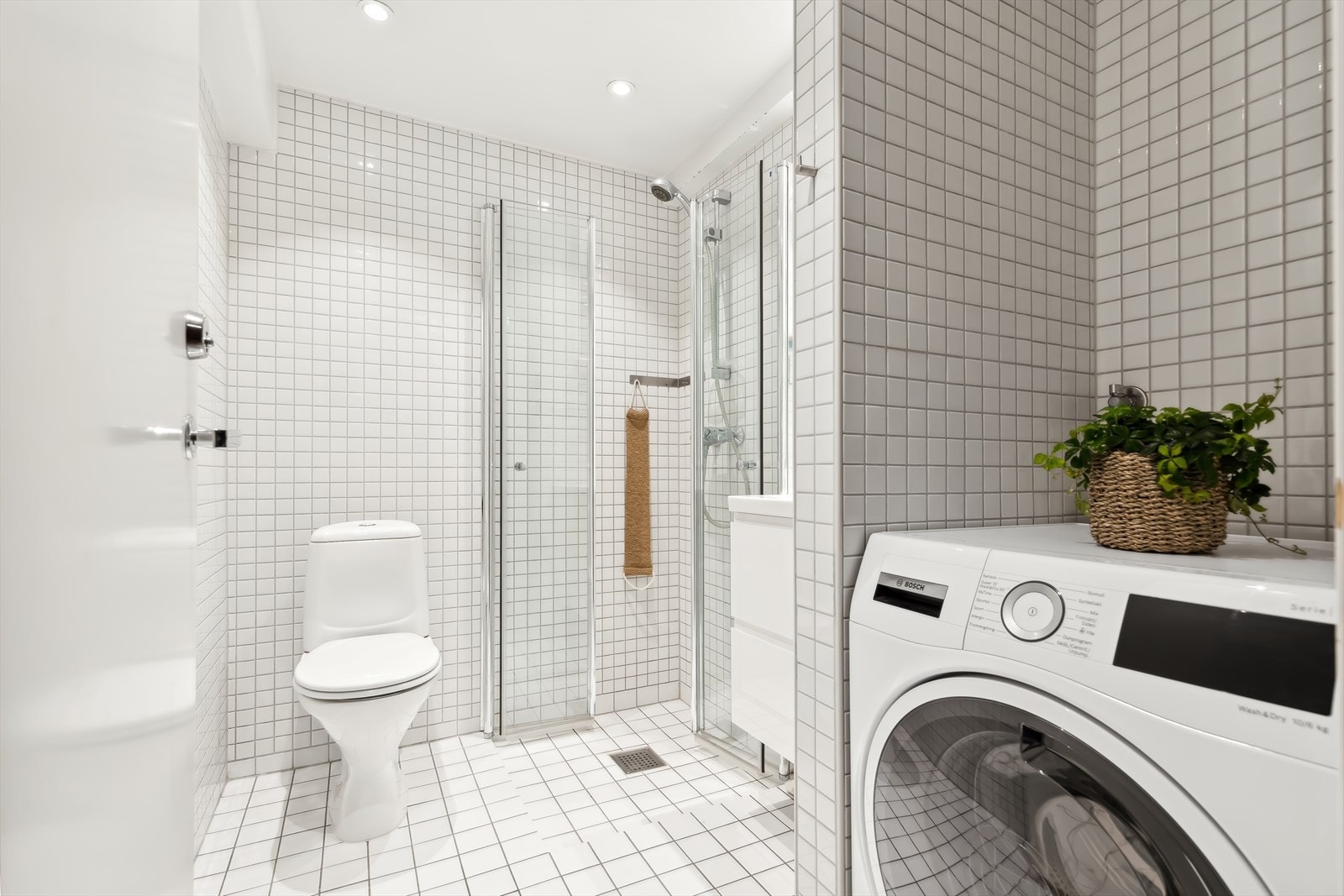 Flott flislagt bad, hjørnedusj med glassdører og opplegg for vaskemaskin. Galleribilde