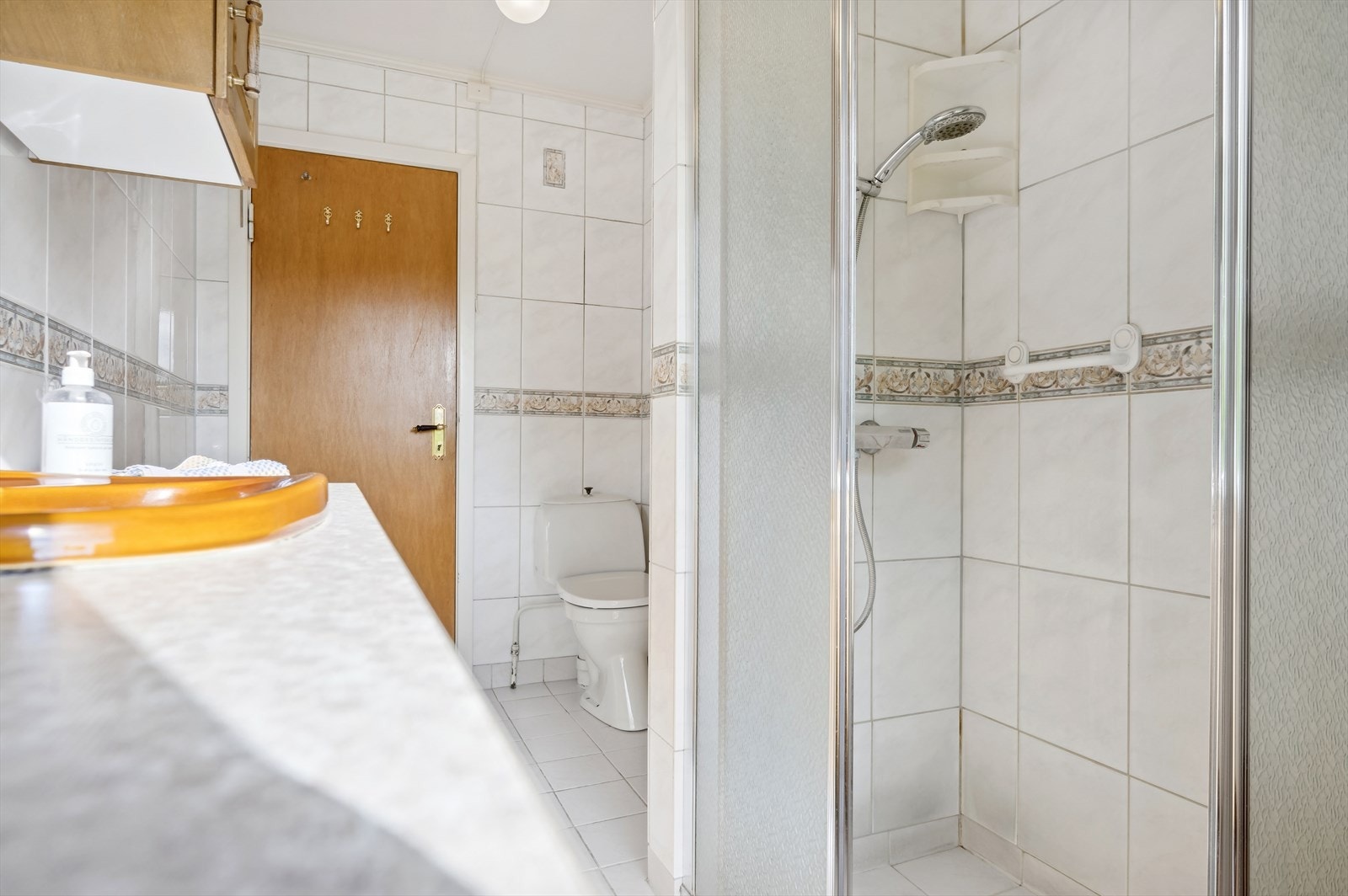 Badet innredet med toalett, bidé, dusjhjørne med glassdører og baderomsinnredning med servant og overskap. Galleribilde