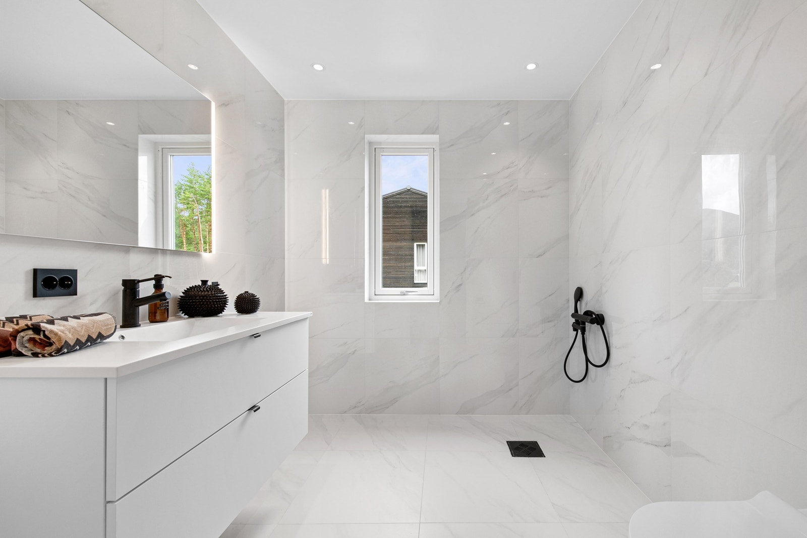 Flott flislagt bad i 2. etasje med hvite lekre fliser på gulv og vegger. Hvit innredning med servan. Speil med sidelys. Innfelte spotter i tak Galleribilde