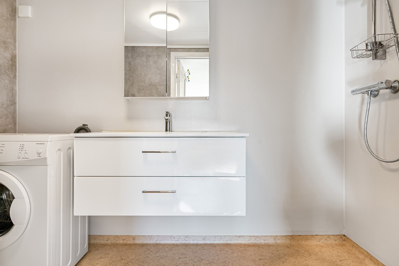 Badet har gulvbelegg og baderomsplater på vegger. Opplegg for vaskemaskin. Galleribilde