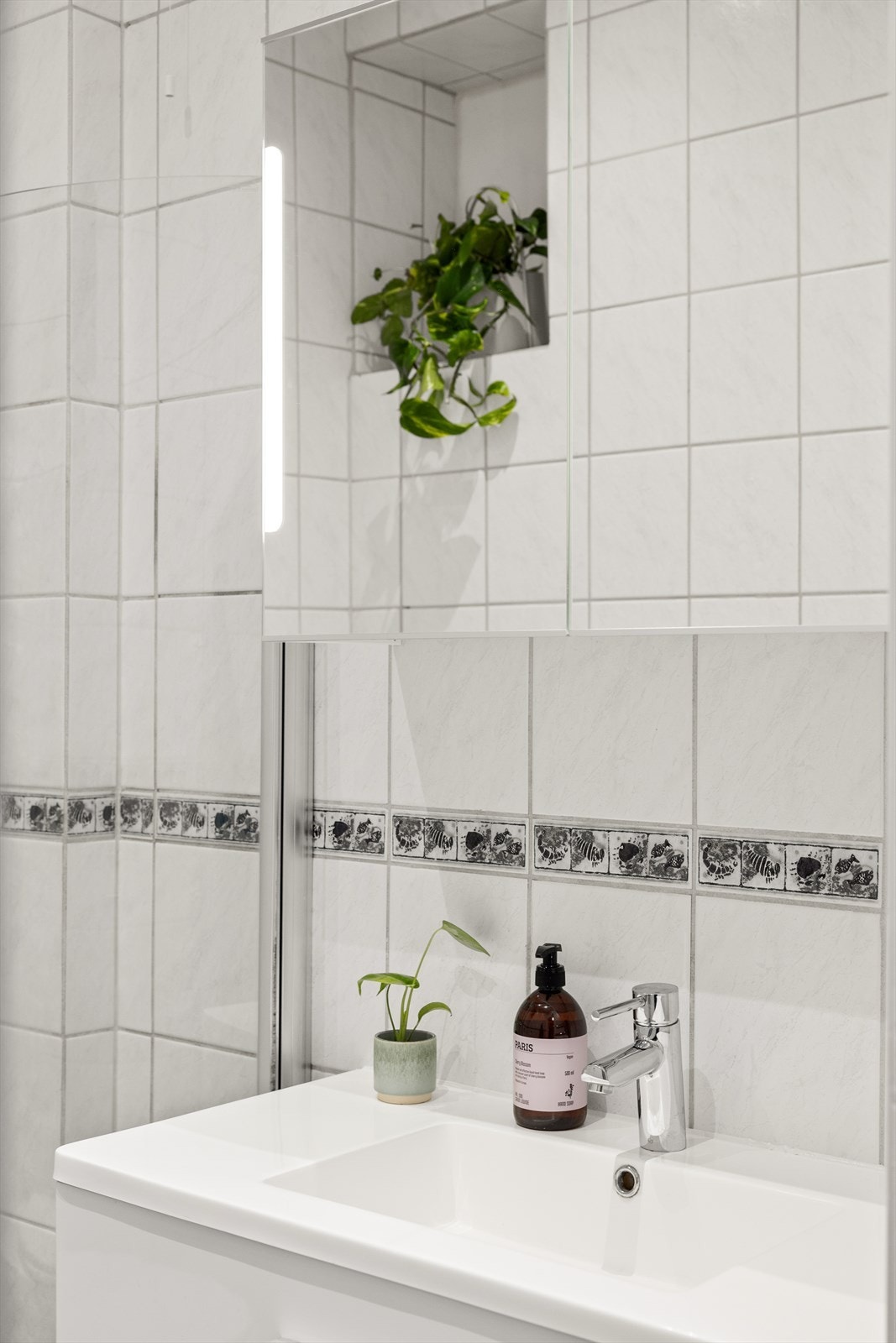 Badet er utstyrt med veggmontert toalett, dusjhjørne med herdet glassvegger og -dør, samt servant med skap, speil og belysning. Servantskap og overskap ble byttet av eier i 2016. Galleribilde