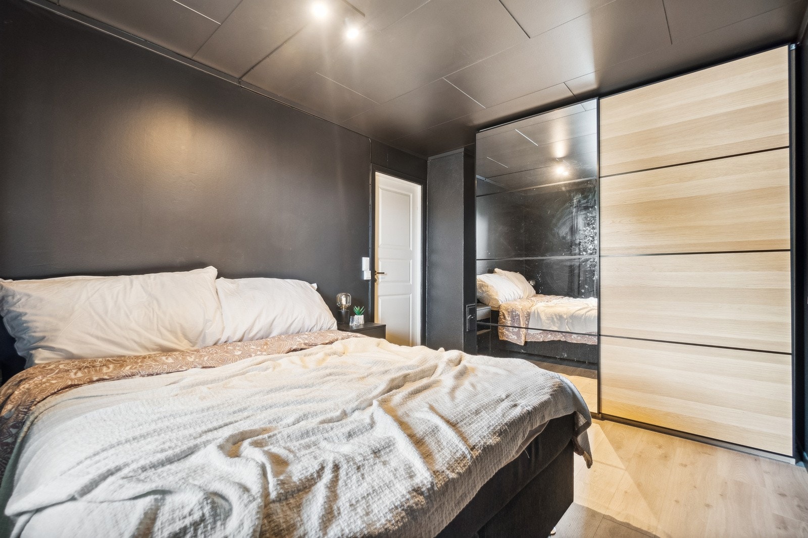 Hovedsoverommet har en innbydende utførelse med mørke vegger mot det lyse gulvet, og et stort garderobeskap med skyvedører. Galleribilde