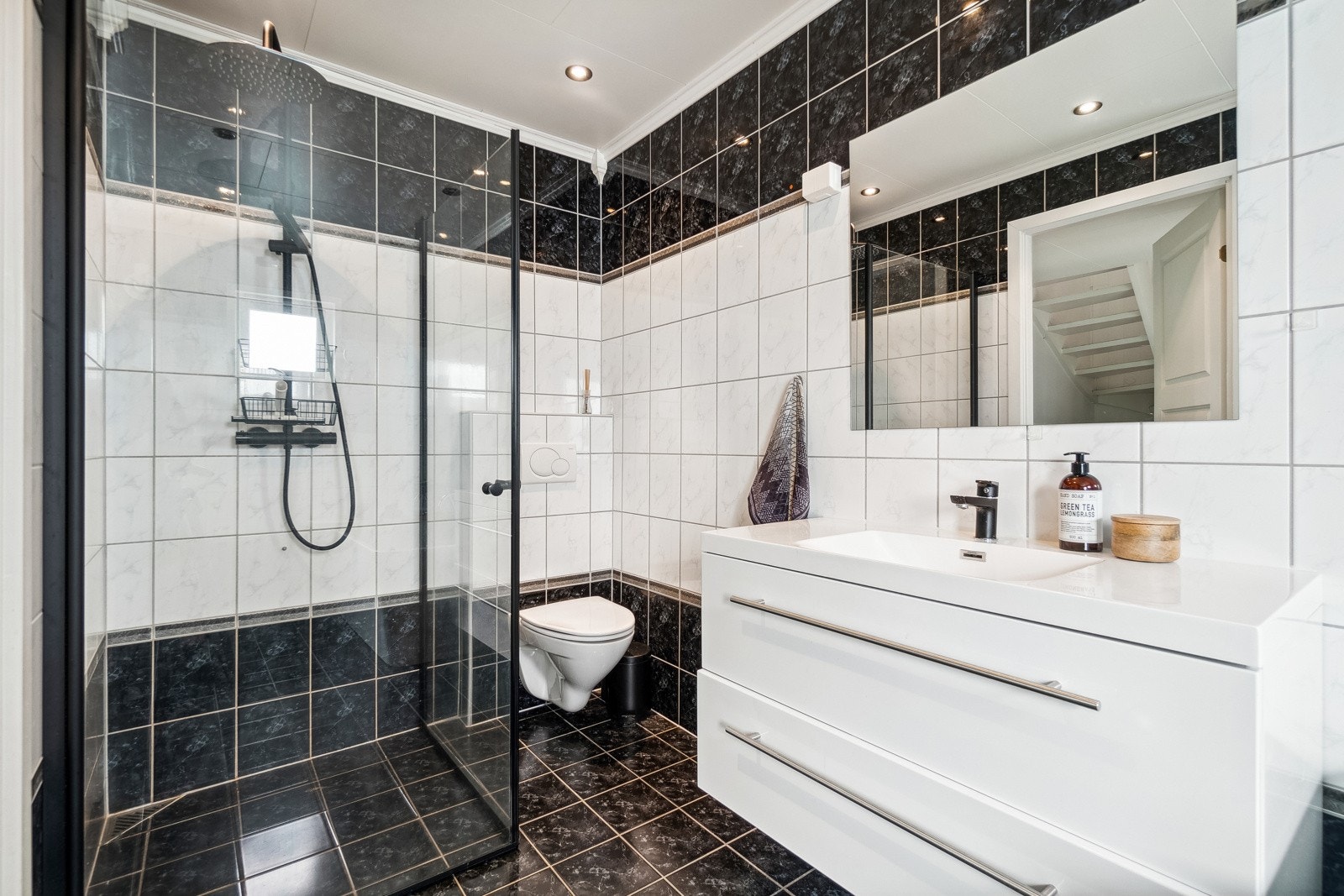 Boligens bad fremstår tidløst med en kombinert mørk og lys utførelse på gulv, vegger og innredning. Galleribilde
