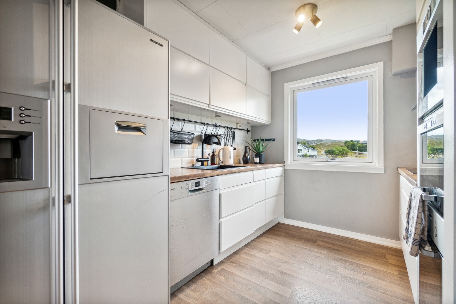 Kjøkkenet har en delvis åpen løsning mot stuen, og fremstår tidløst takket være en nyere innredning med hvite slette fronter med innfelte håndtak. Galleribilde