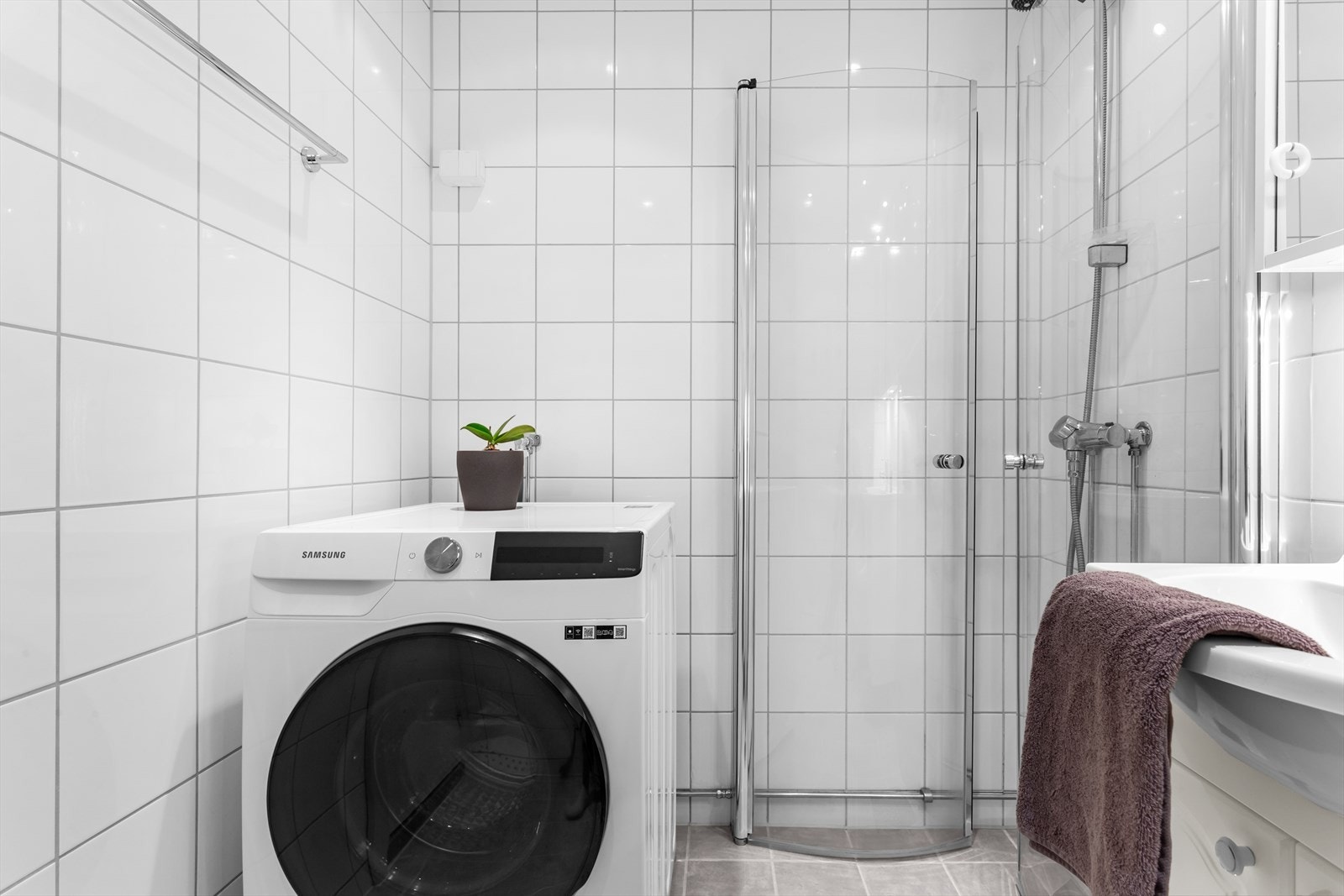 Badet inneholder stilren innredning, dusjhjørne, veggmontert wc og opplegg til vaskemaskin. Galleribilde