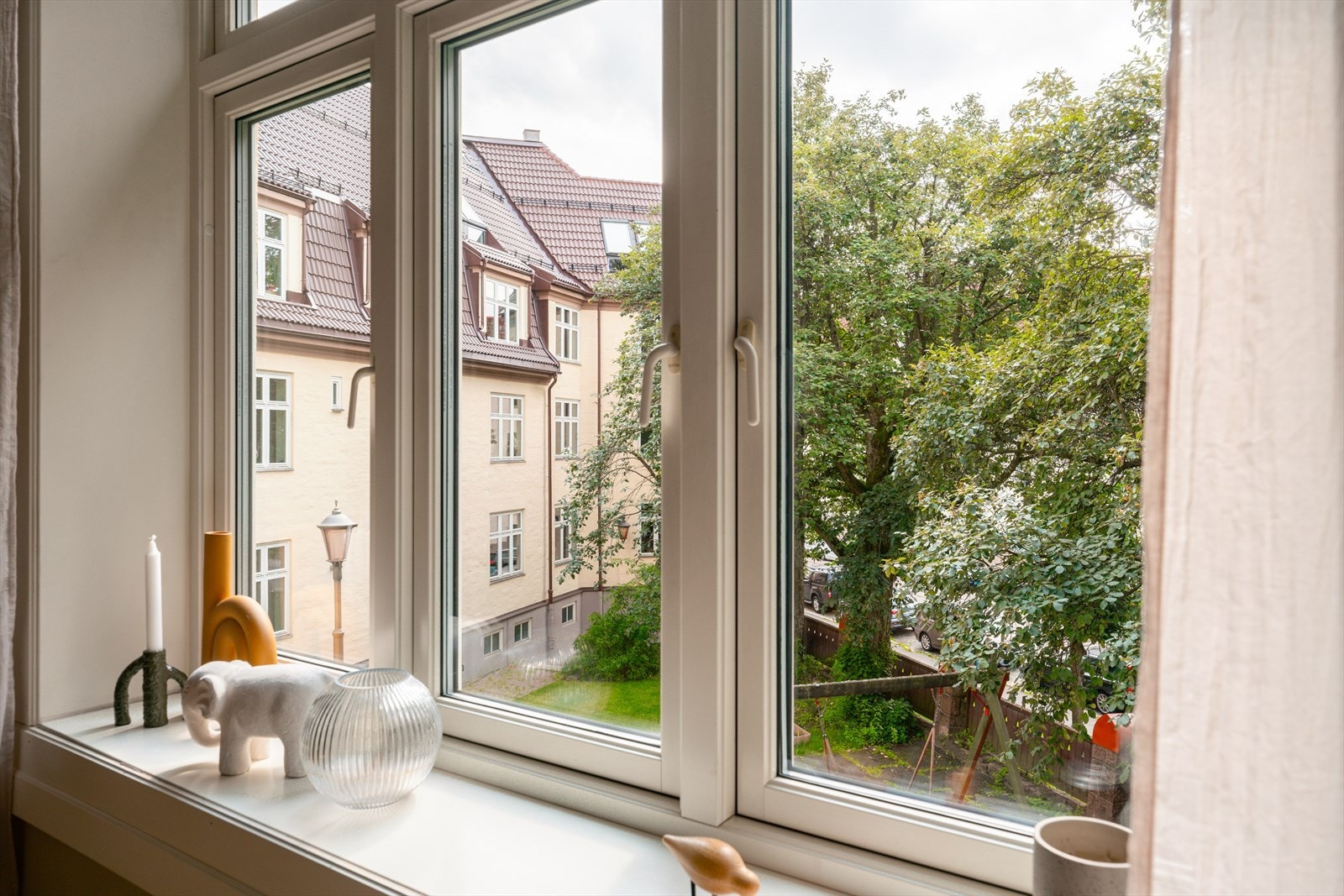 Stuen vender ut mot en idyllisk, grønn bakgård. Galleribilde