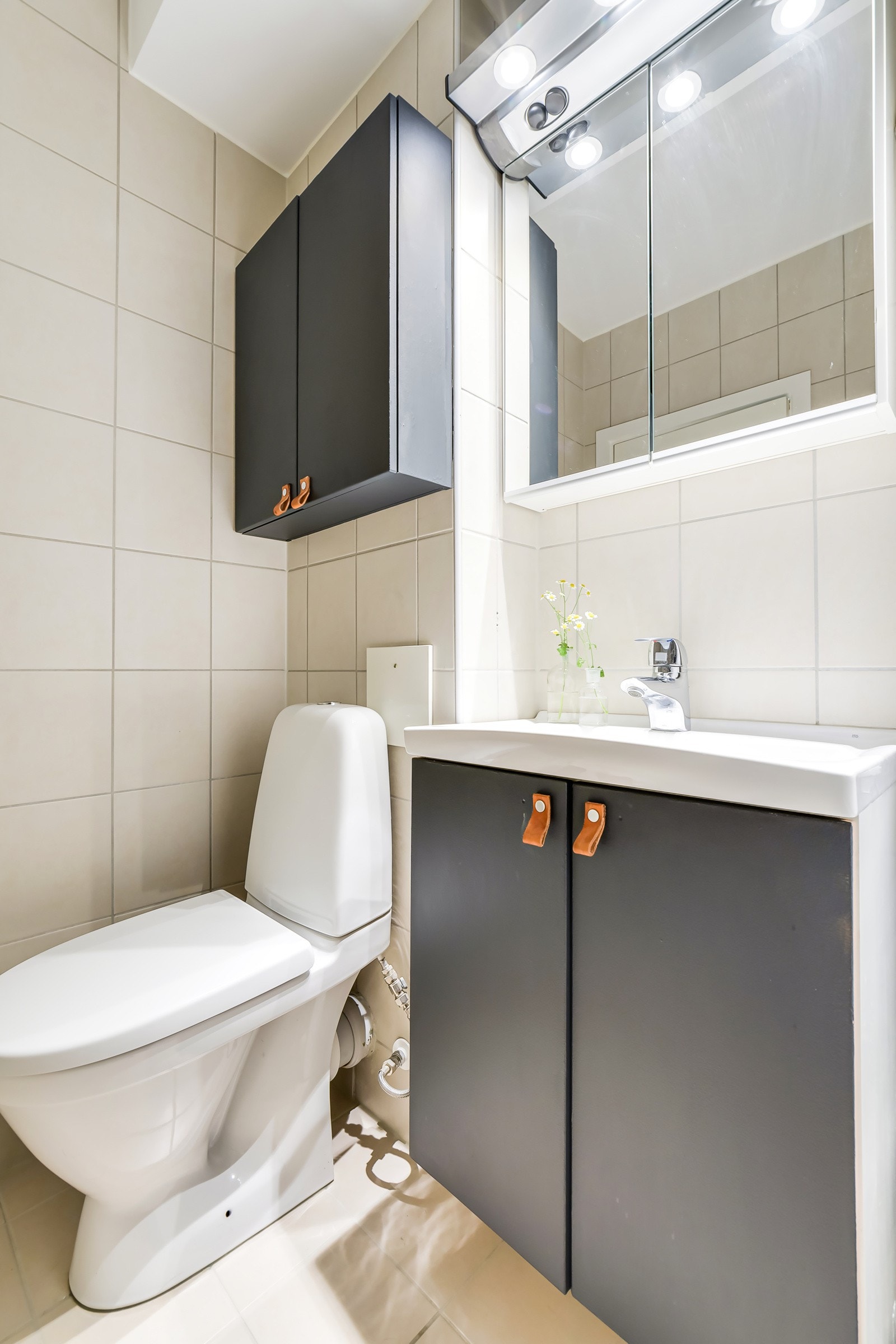 Baderommet inneholder servant, servantskap, speilskap med overbelysning og stikkontakt, dusjhjørne med regnfallsdusj og toalett. Galleribilde