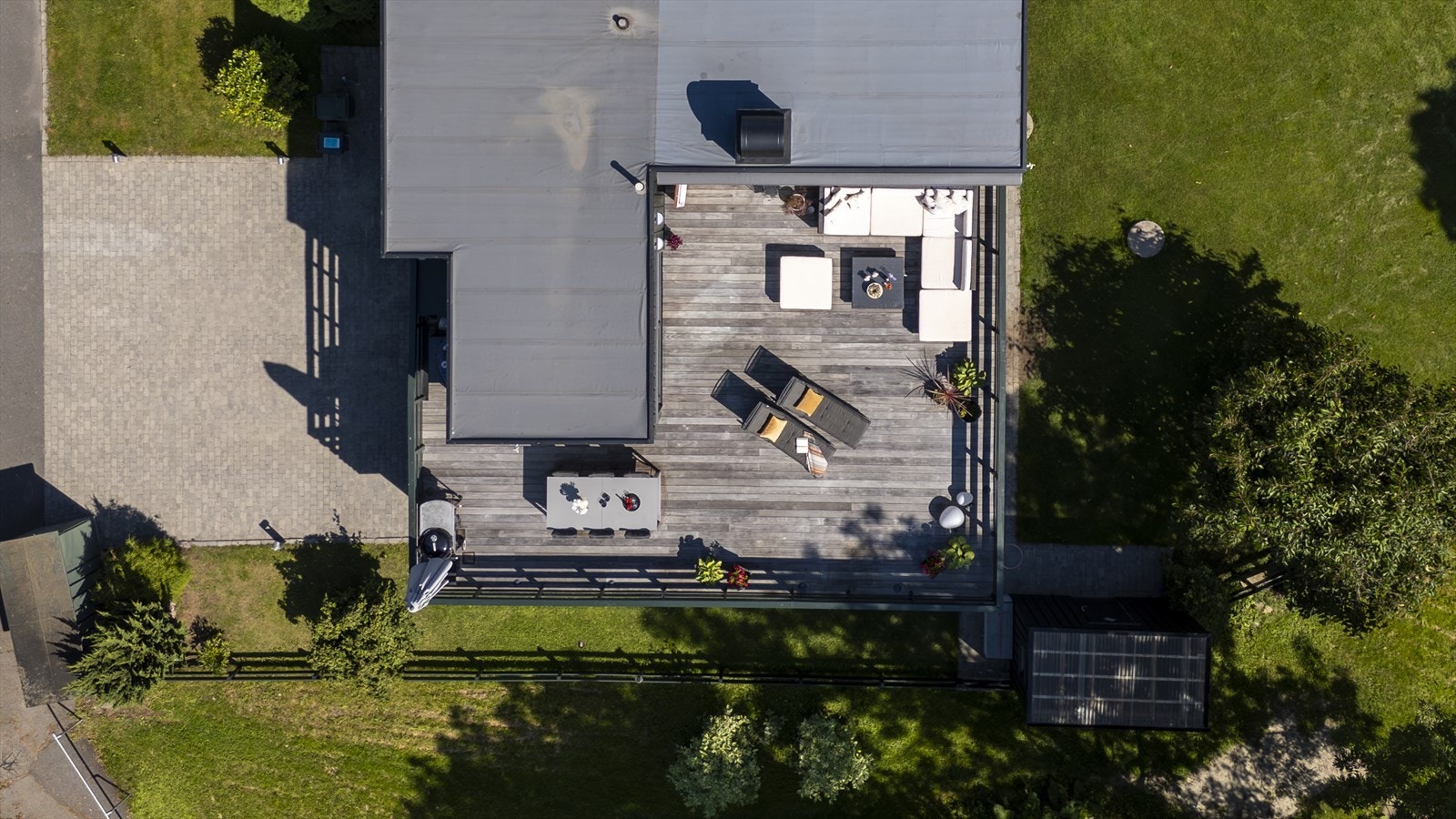 Stor, solrik tomt på ca. 443 kvm som er pent opparbeidet med belegningsstein, plen og diverse beplantning. Frittliggende utebod på 4 m² og en dobbel garasje under terrasse. Oppvarmet nedkjørsel (3 striper) til bil/gangfelt og sensorstyrt utebelysning. Galleribilde