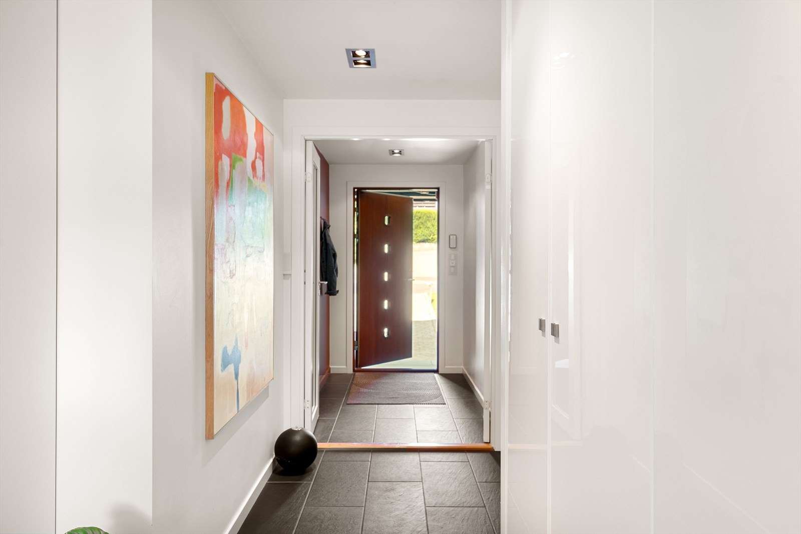 Entréen er nøye utformet med store mørke fliser med elektriske varmekabler, glatte hvitmalte vegger og downlights i taket. Galleribilde