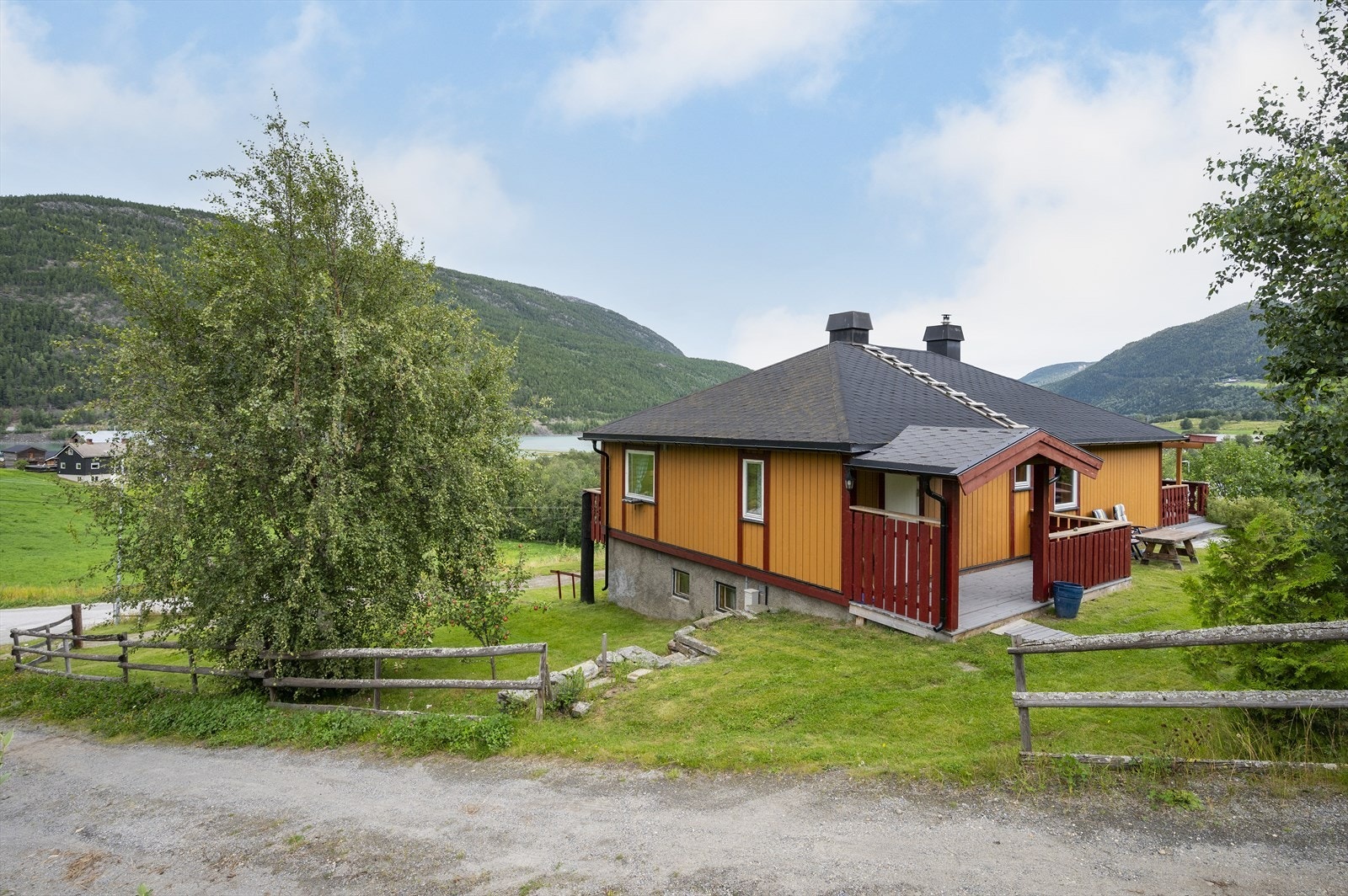 Tomten er pent opparbeidet med plen, murer, busker og trær. Galleribilde