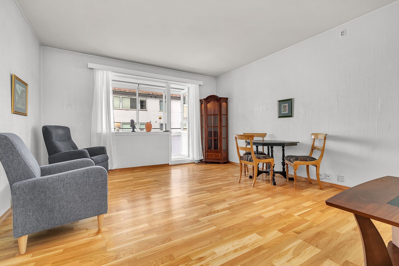 Stue med parkett på gulv og utgang til innglasset balkong. Galleribilde