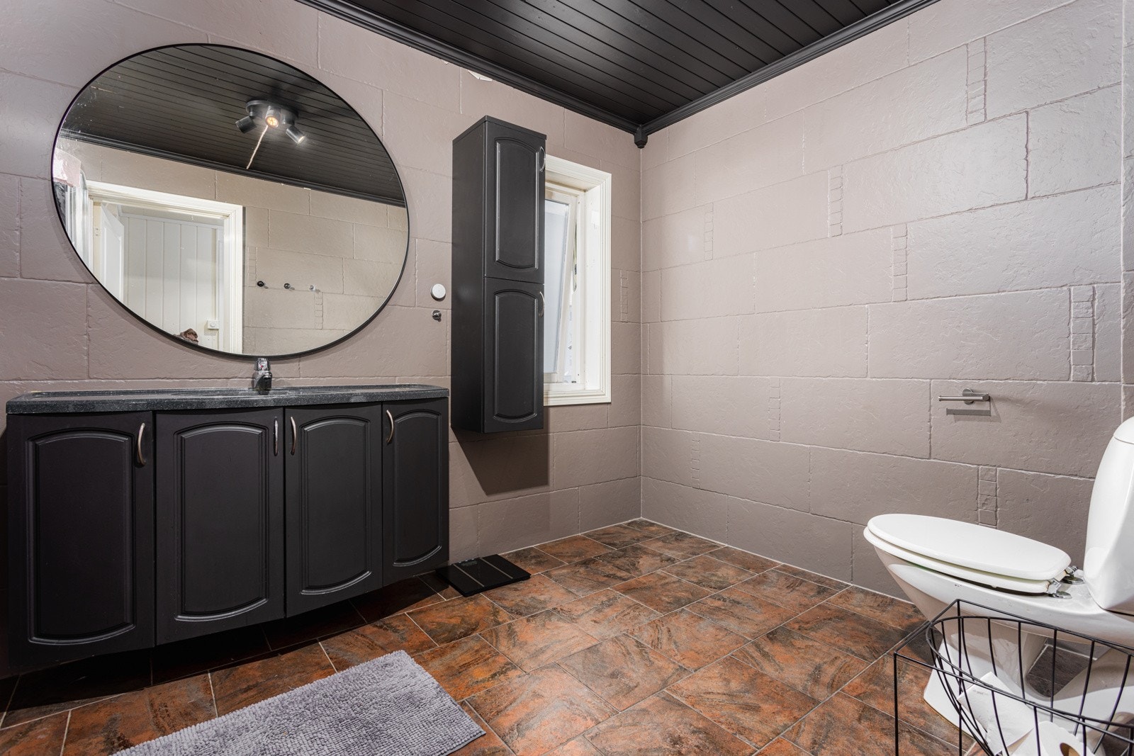 Badet har beigemalte fliser på veggene og sort baderomsinnredning. Et bad med god plass og detaljer som er gjennomgående i hele leiligheten. Galleribilde
