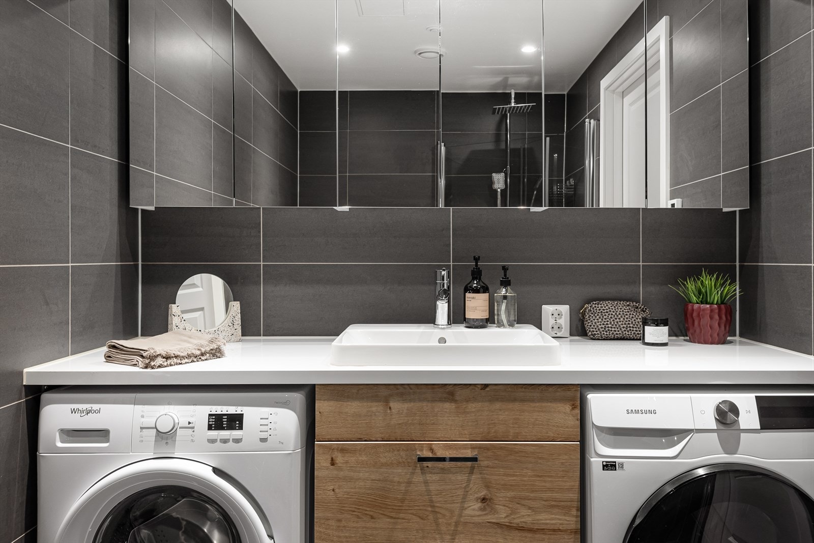 Over servanten er det satt opp overskap med speilfronter. Videre har badet opplegg for vaskemaskin, samt plass til tørketrommel under benkeplaten. Galleribilde