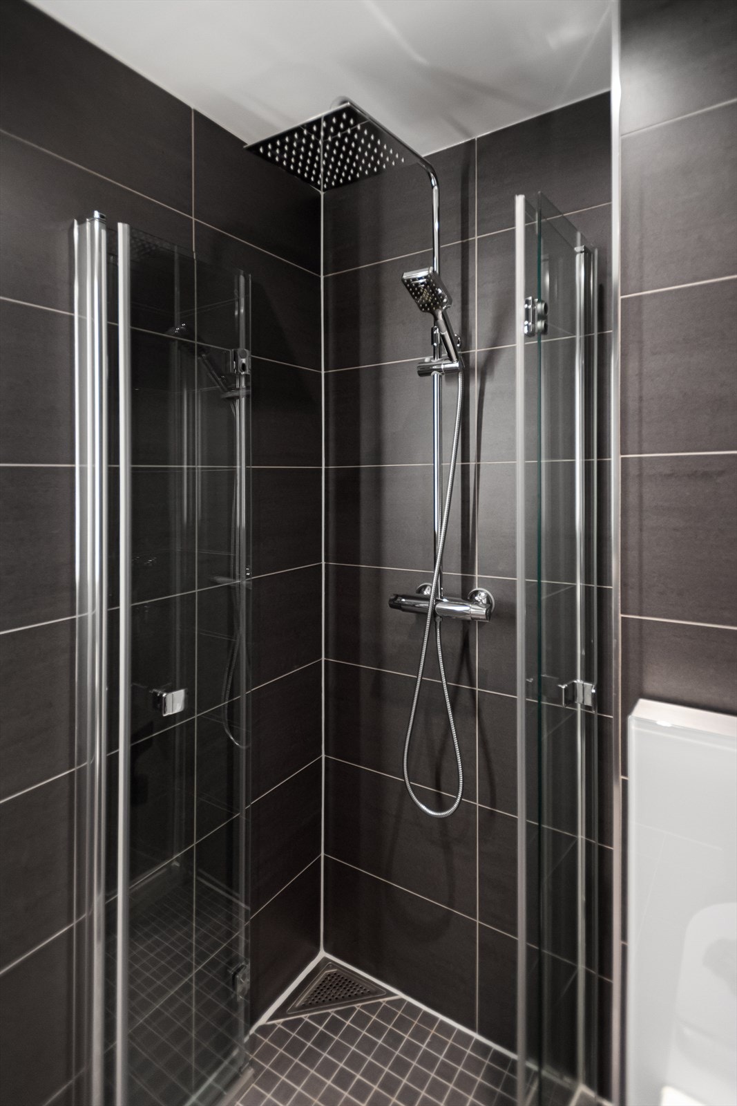 Rommet har dusj på gulv, veggfestet klosett samt servant med benkeskap. Galleribilde