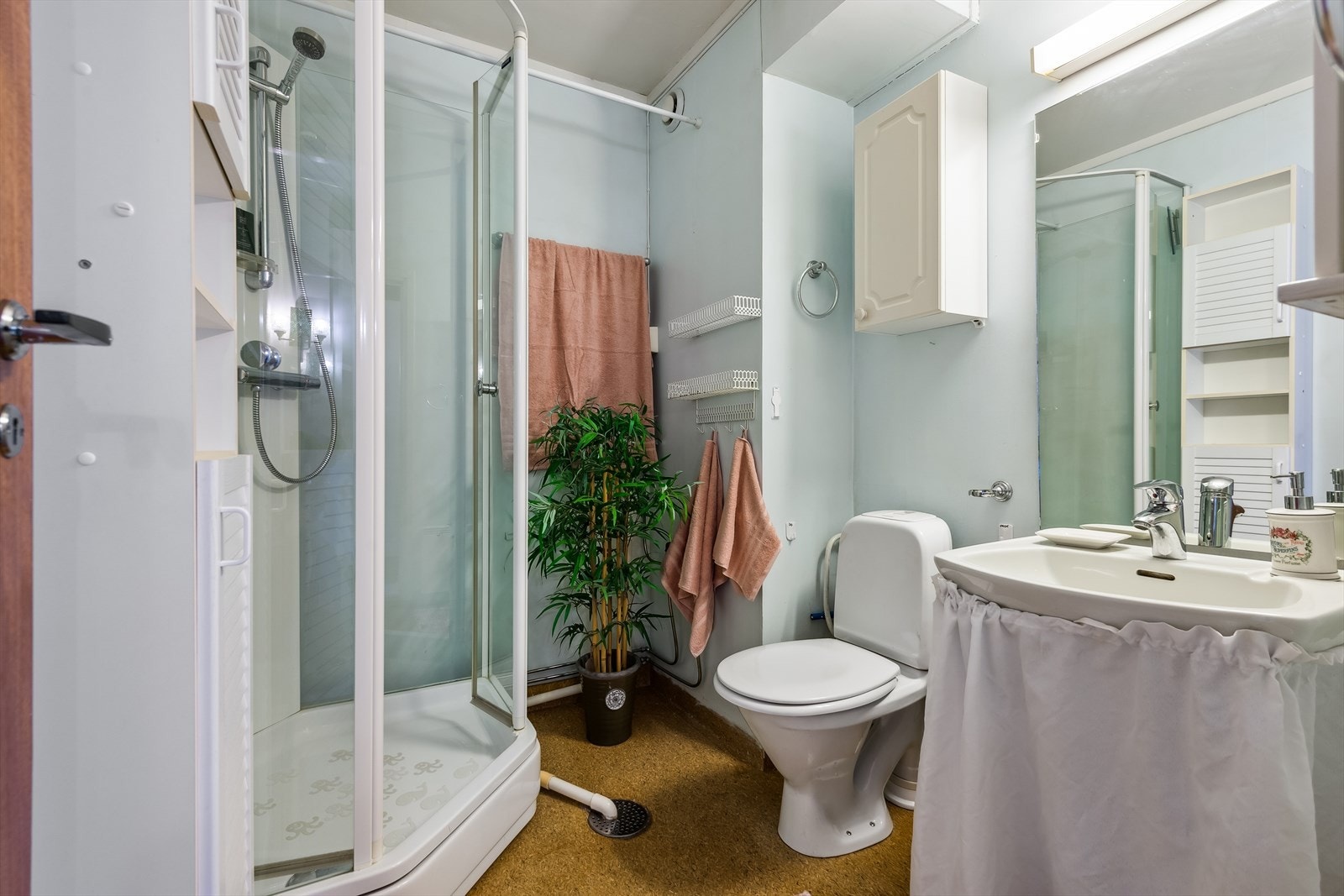 Baderommet har lyse vegger og er innredet med toalett, dusjkabinett, speil og diverse skap/hyller. Galleribilde