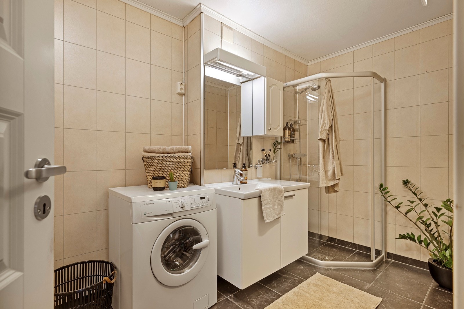Badet måler 6 kvm og er utstyrt med en praktisk baderomsinnredning, opplegg for vaskemaskin og dusjhjørne. Galleribilde