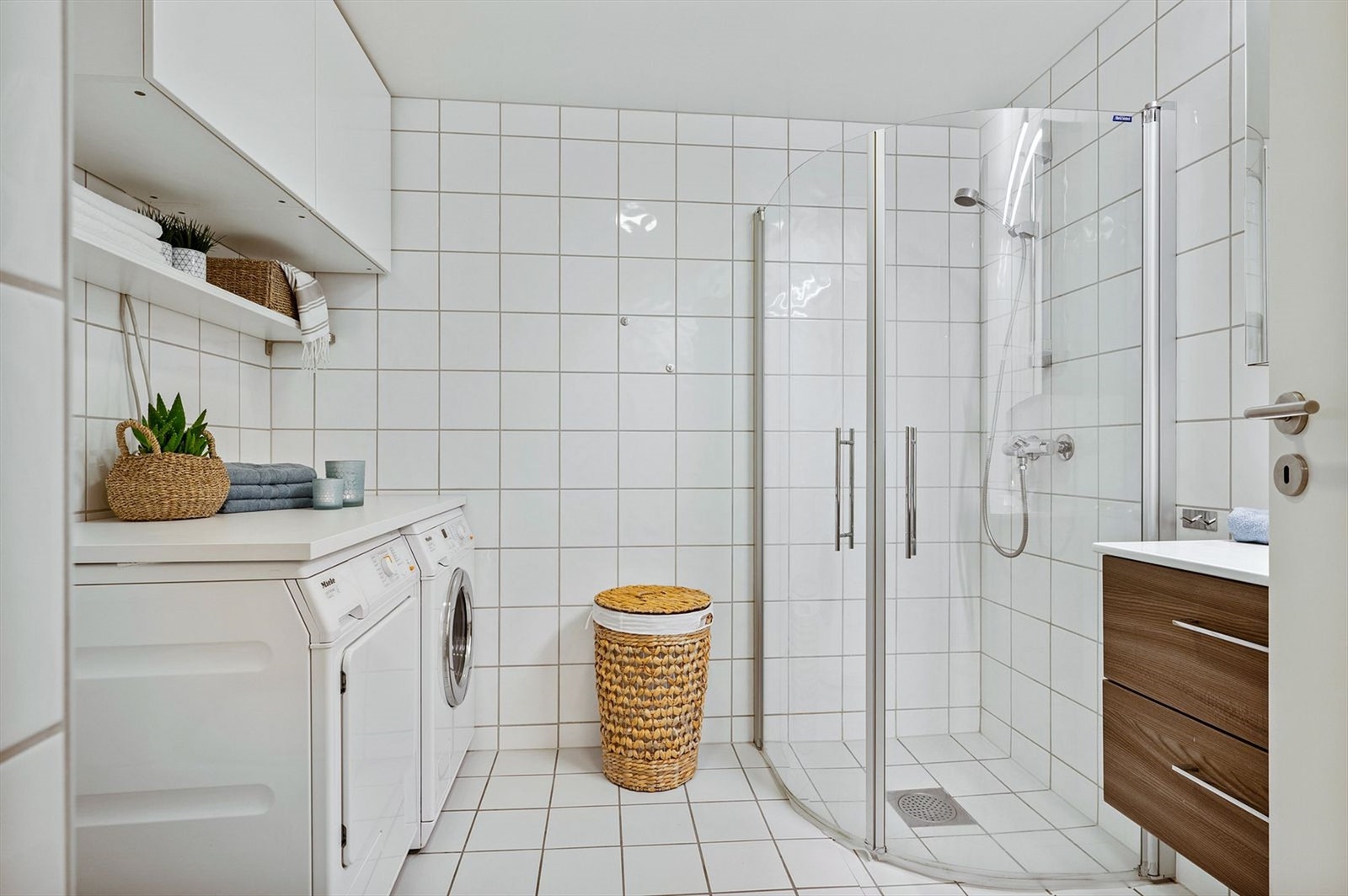 Bader et flislagt med plass til vaskemaskin og tørketrommel. Benkeplaten over maskinene medfølger i salget Galleribilde