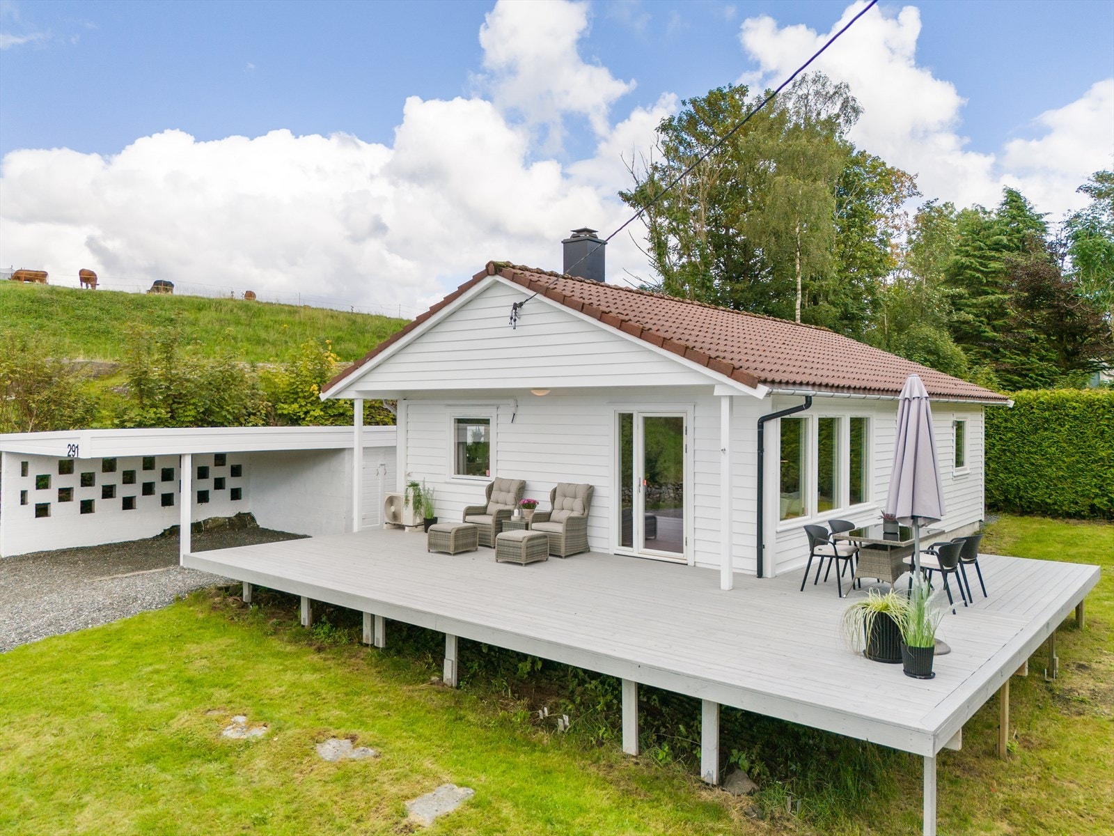 Tomten er opparbeidet med terrasse, carport, plen og gruset innkjørsel og parkeringsmulighet. Galleribilde