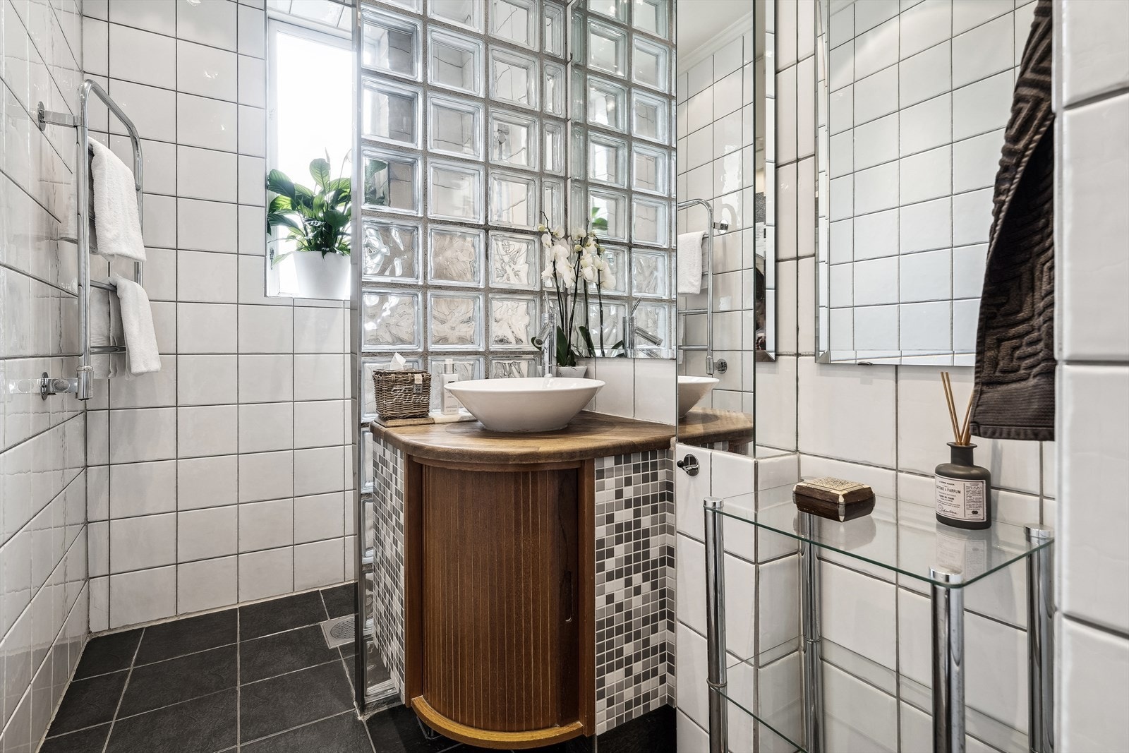 Badet er utstyrt med servant med servantskap, veggfestet toalett med skjult sisterne, dusj med en glassbyggerstensvegg. Det er lufteluke i taket og tilluft i døren. Galleribilde