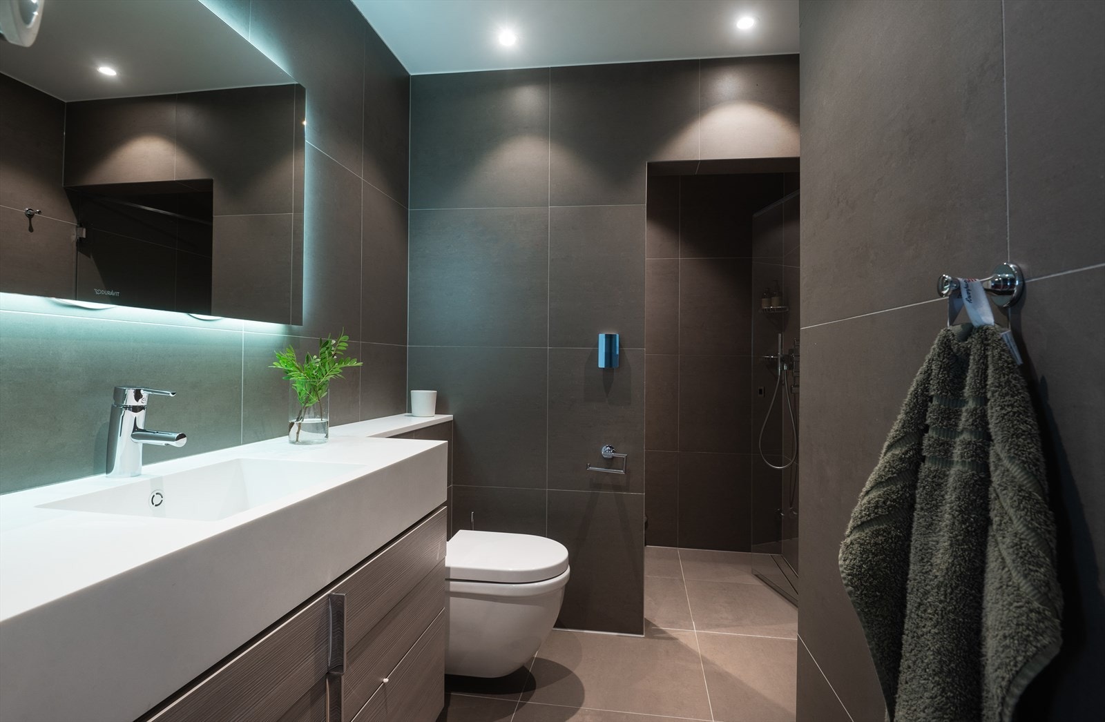 Spabad fra 2017 med flislagt gulv med varme, flislagte vegger og senket og malt platehimling med downlights . Galleribilde