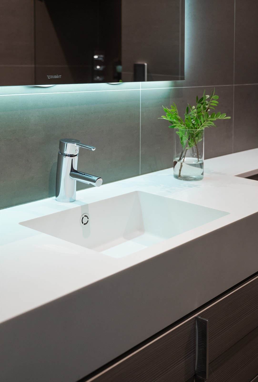 Servant av Corian med underskap, speil med lys over servant, høyskap, 2 stk. håndkletørkler og vegghengt toalett. Galleribilde