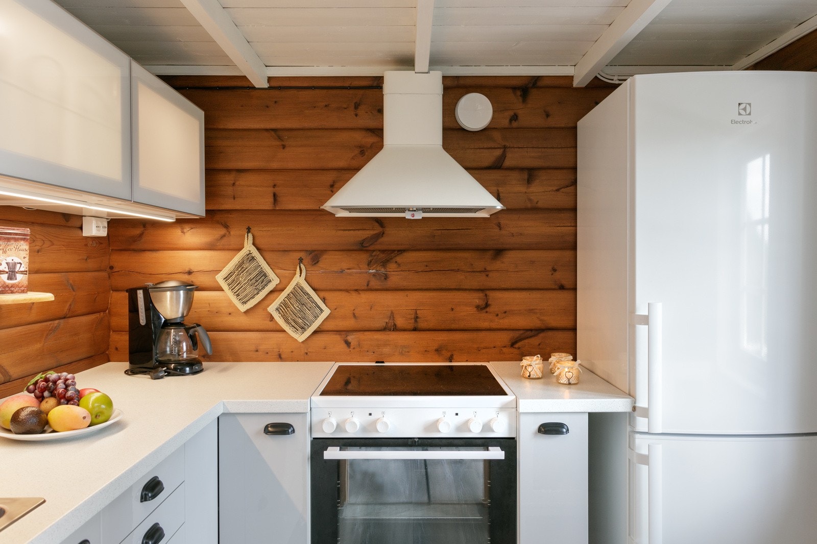 Kjøkkenet har vippeskap med lys og kjøkkenventilator over komfyr Galleribilde