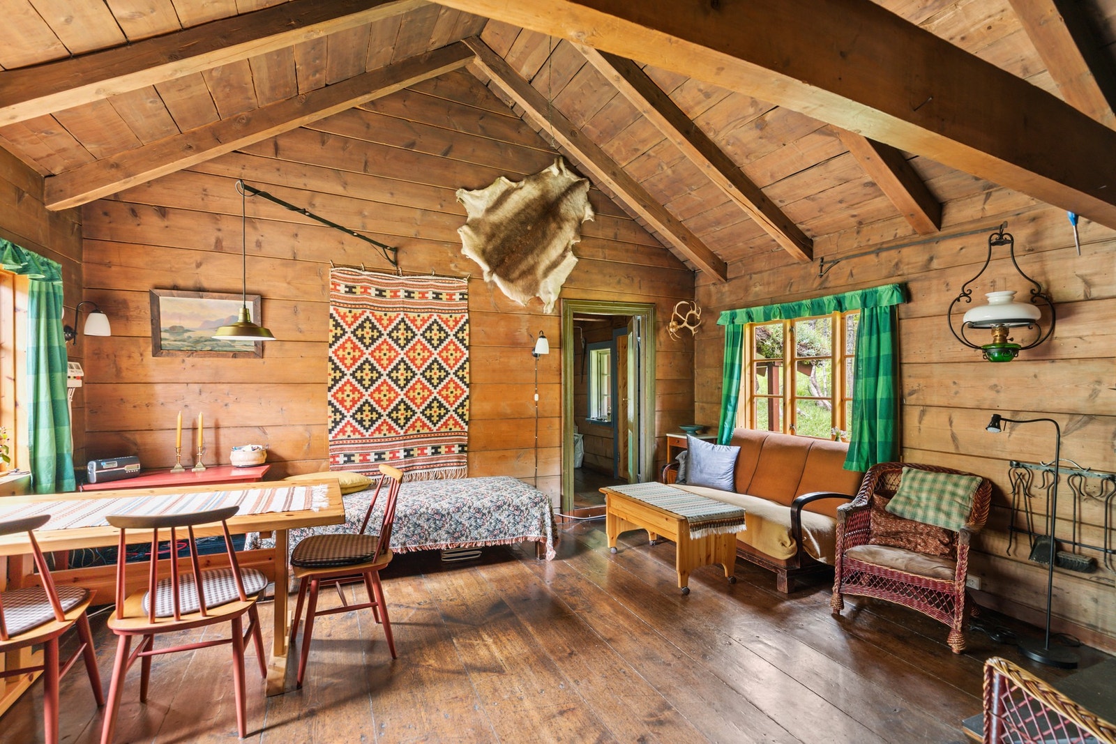 Hytten er bygd med tradisjonelle materialer med laftede vegger og gulv av lakkerte, brede trebord Galleribilde