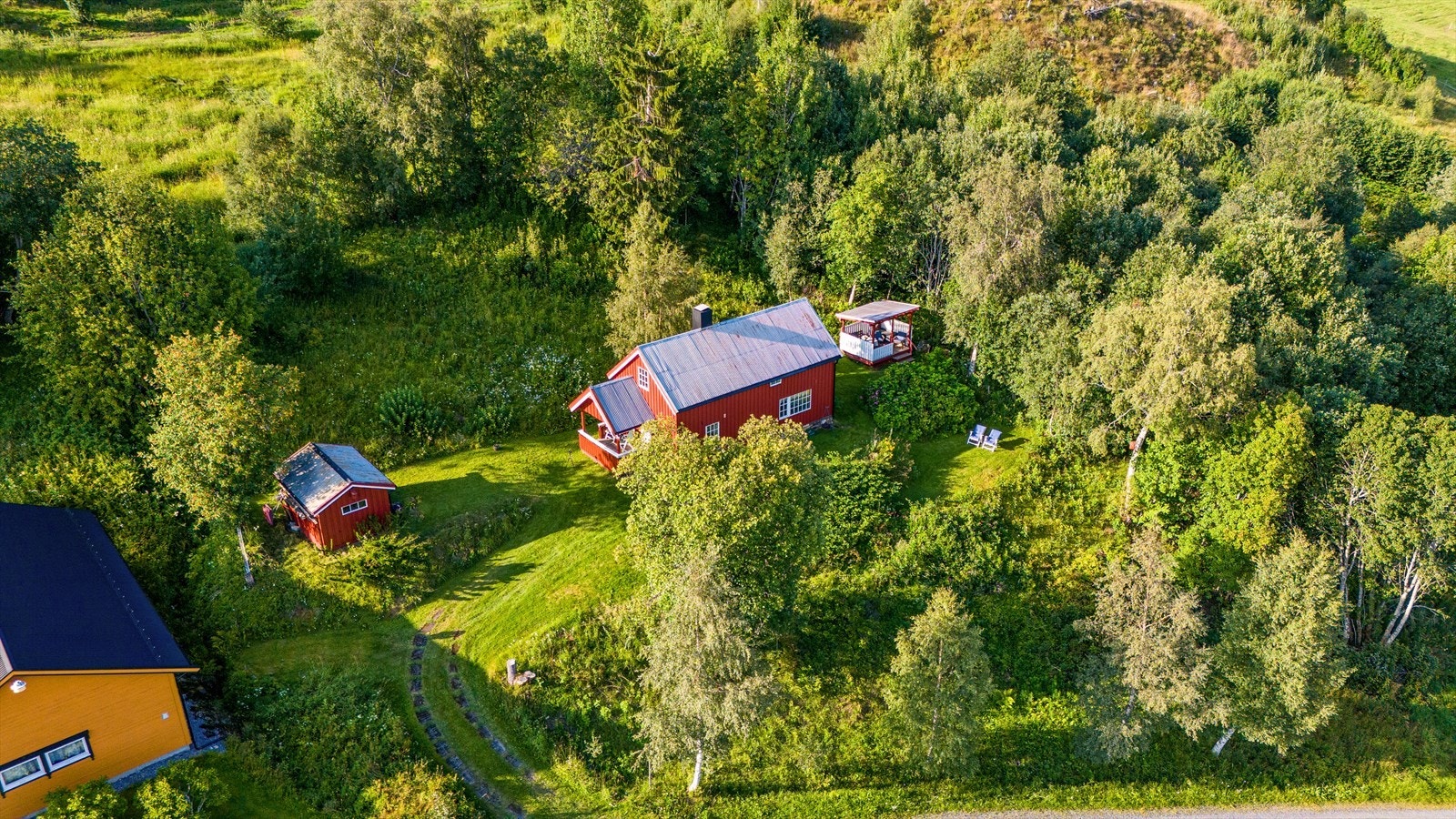 Dronebilde, det er bilvei helt frem og innlagt sommervann. Uthus og fine uteområder. Galleribilde
