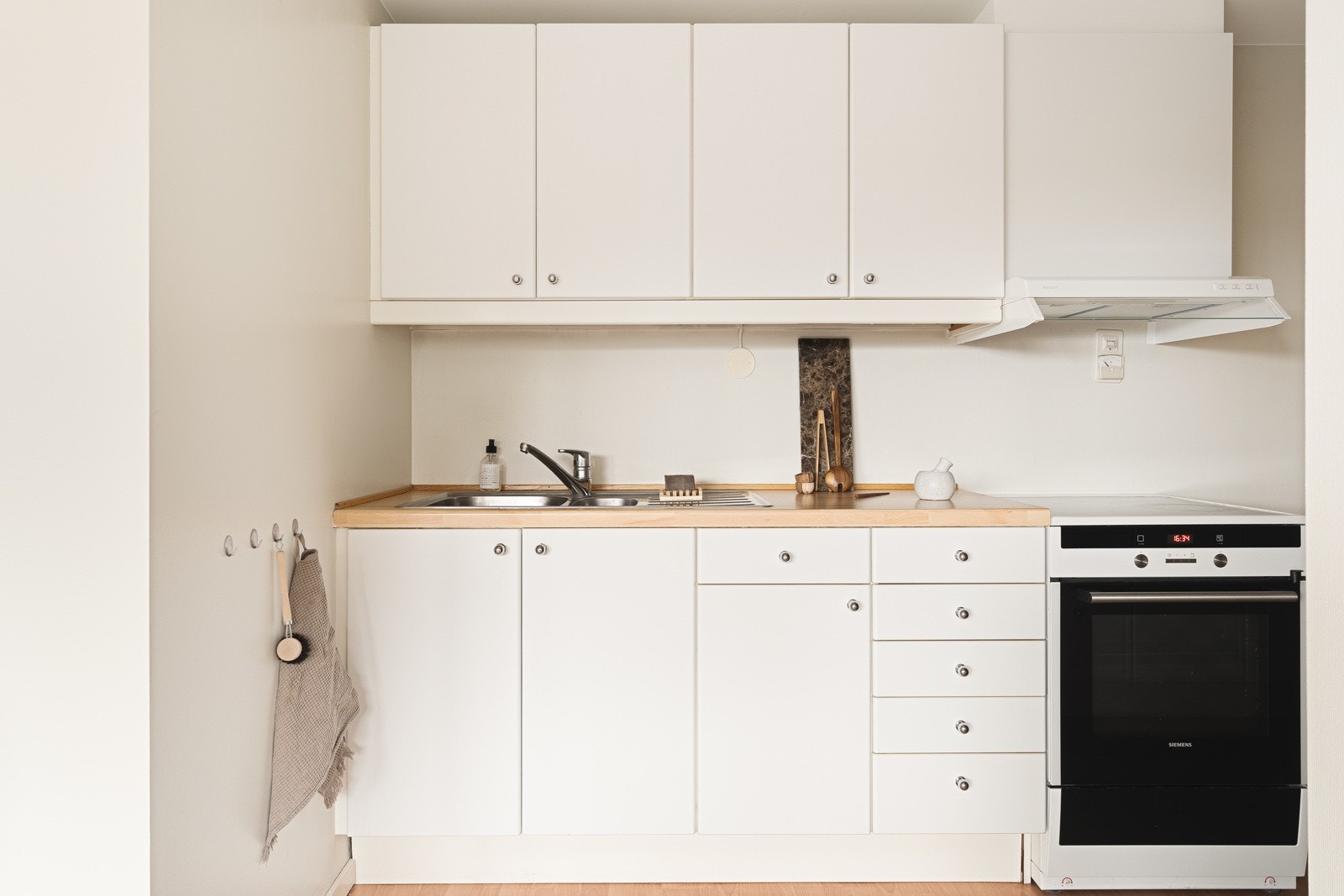 Kjøkken med slette hvite fronter og laminat benkeplate med nedfelt vask av stål. Galleribilde