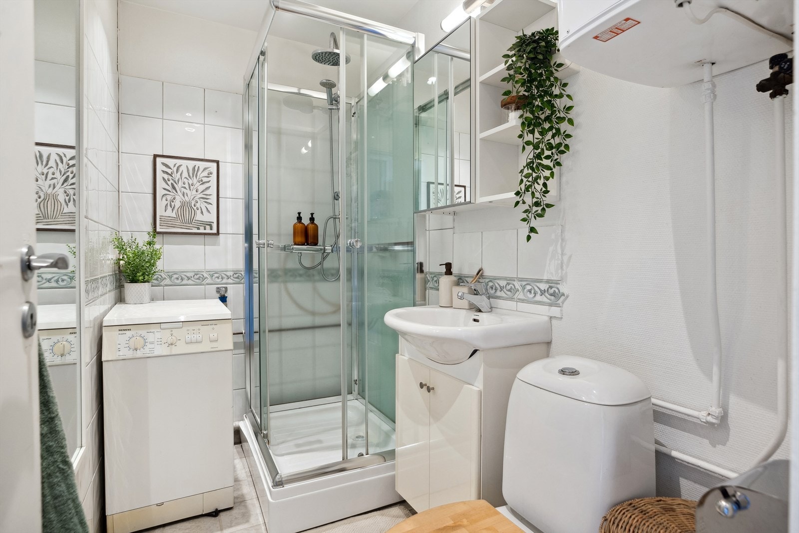 Lyst og flislagt bad på 3 m² med praktisk baderomsinnredning og opplegg for vaskemaskin. Galleribilde