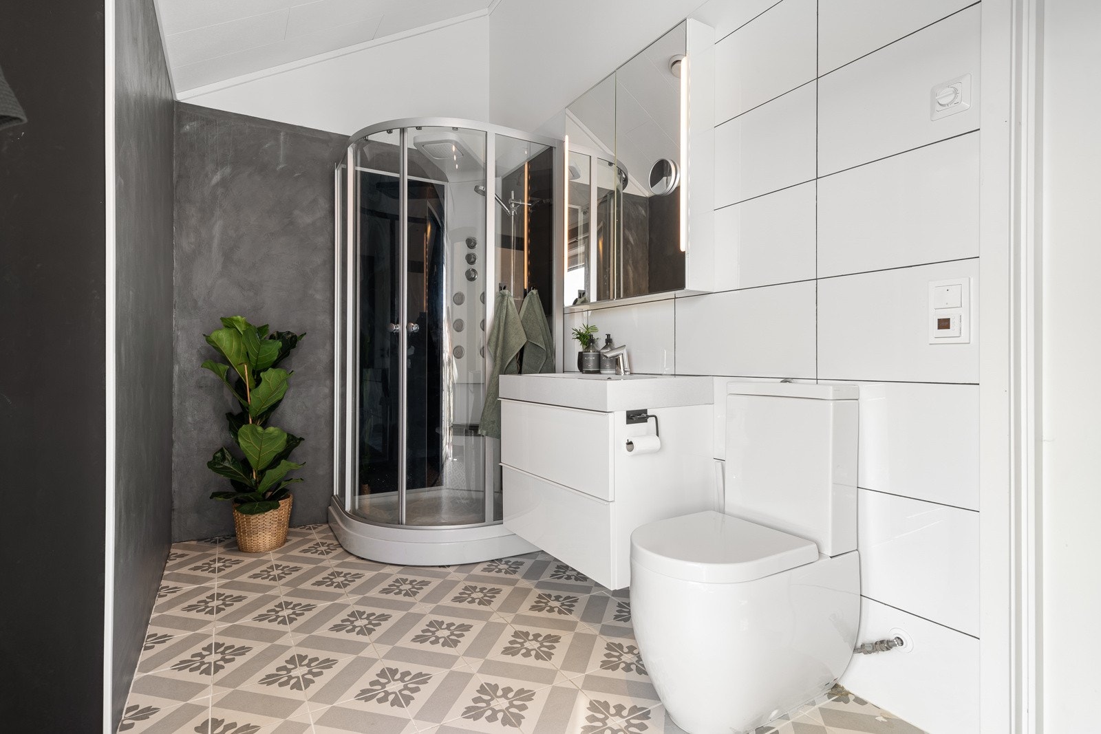 Baderom på loftsetasjen er utstyrt med vegghengt servantinnredning, speilskap med sidelys, dusjkabinett og toalett. Galleribilde