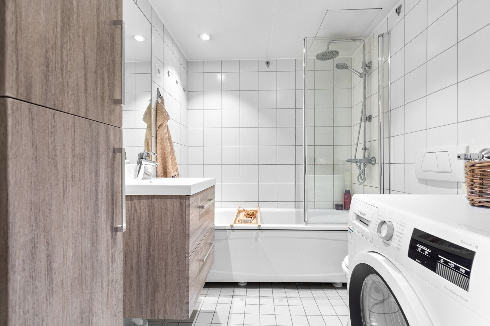 Videre er badet utstyrt med veggmontert toalett og badekar med dusjvegg, regnfallsdusj og hånddusj. Det er opplegg for vaskemaskin og tørketrommel. Galleribilde