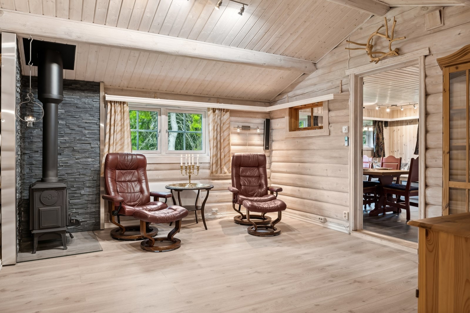 Hytta har flere soner en kan møblere i, her en tilbaketrukken, koselig sone med lenestoler og vedovn som varmer godt på kalde dager. Galleribilde