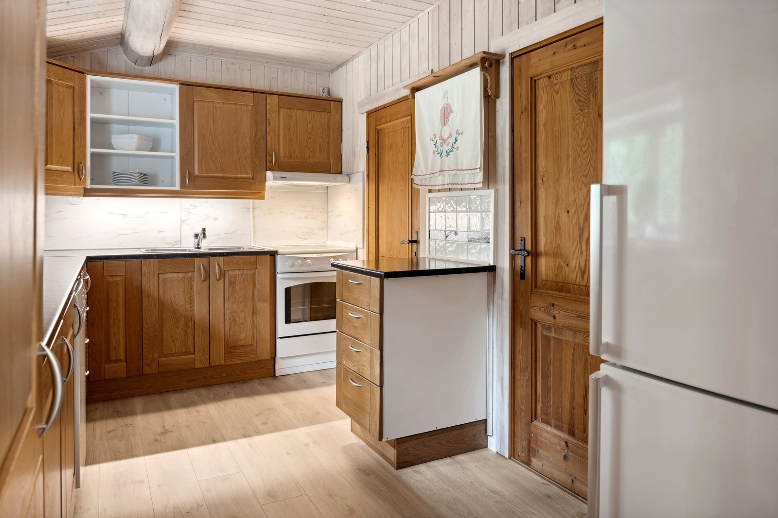 Innredning med laminerte skrog, profilerte fronter, laminat over benkeplate og belysning over benkeplate. Galleribilde