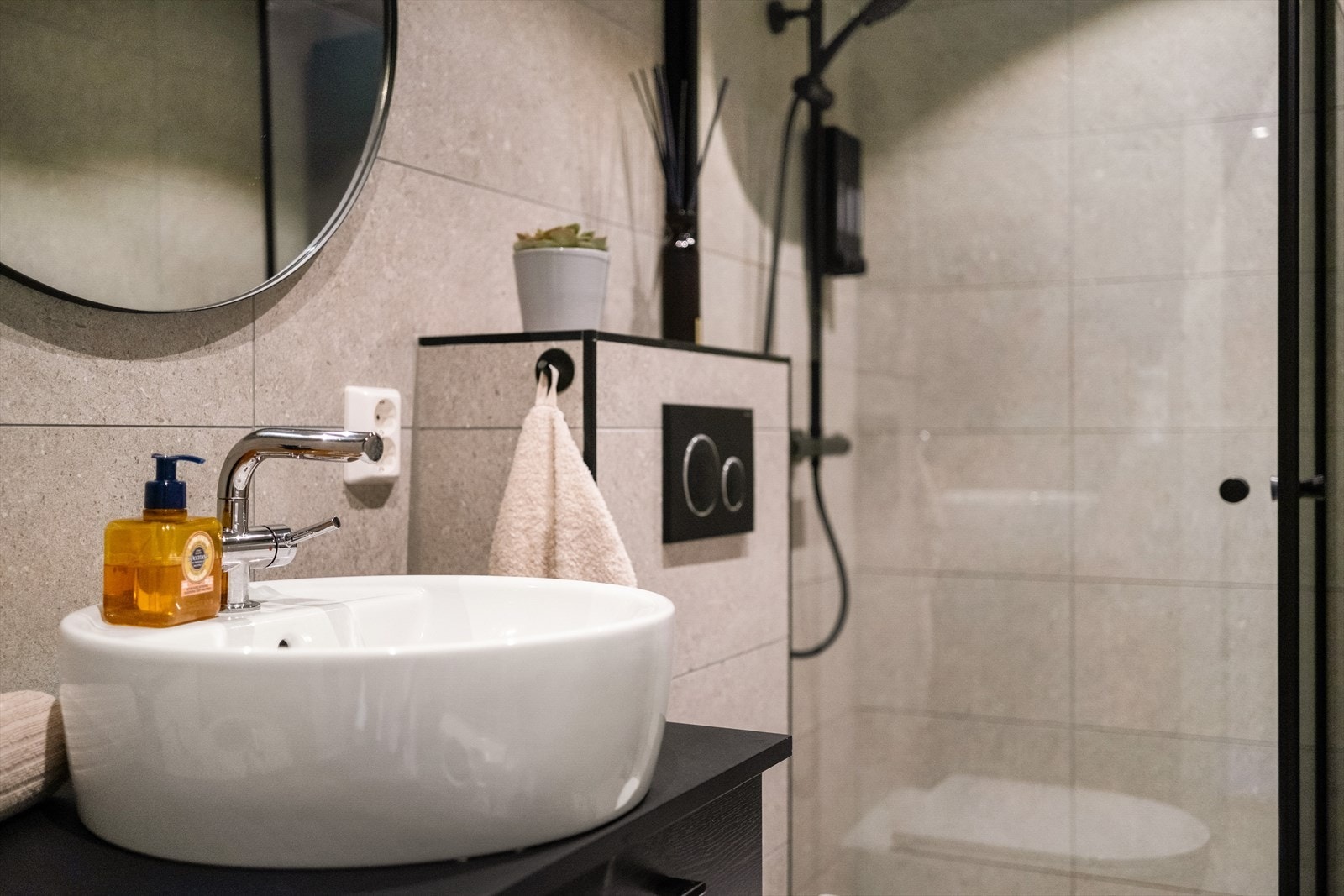 Badet er innredet med servant med underskuffer, speil, dusjhjørne med glassdører og vegghengt toalett. Galleribilde